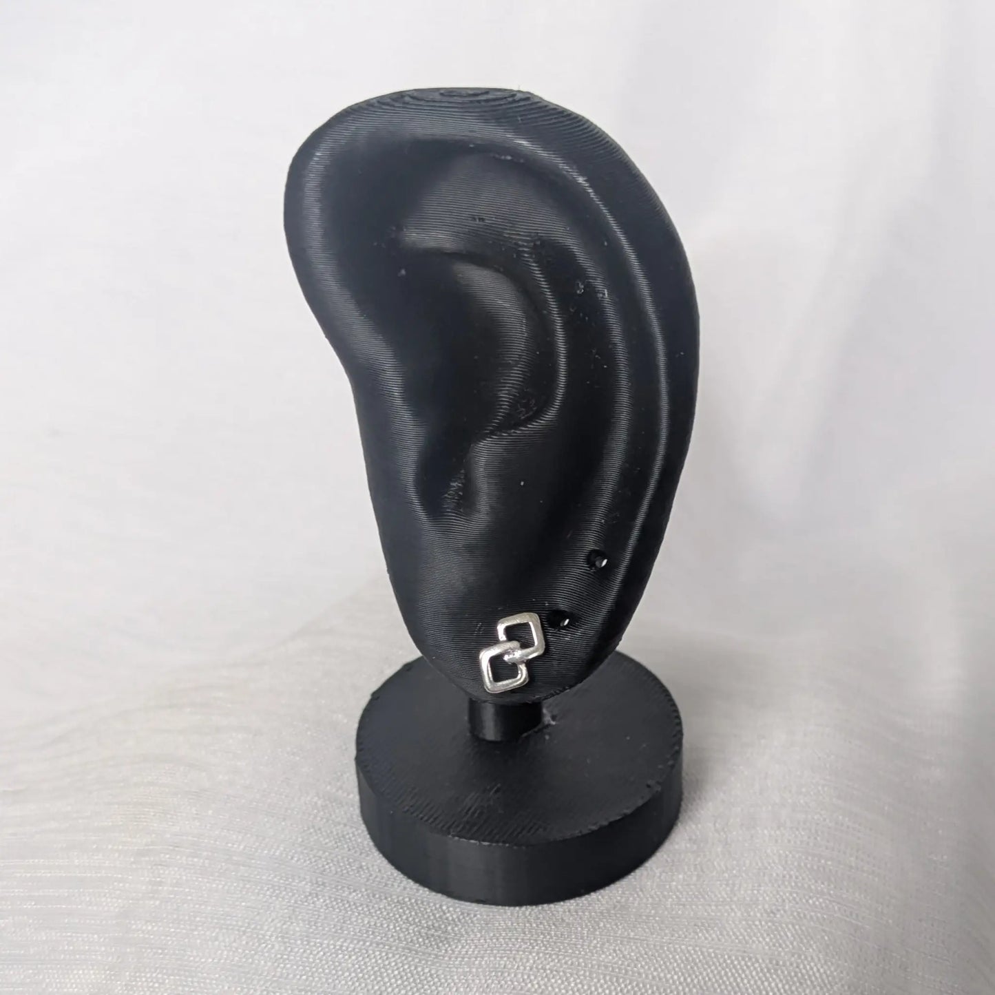 Geometrische Doppel-Rauten Ohrstecker an einem schwarzen Schmuck-Display zur Darstellung der Größe am Ohr.