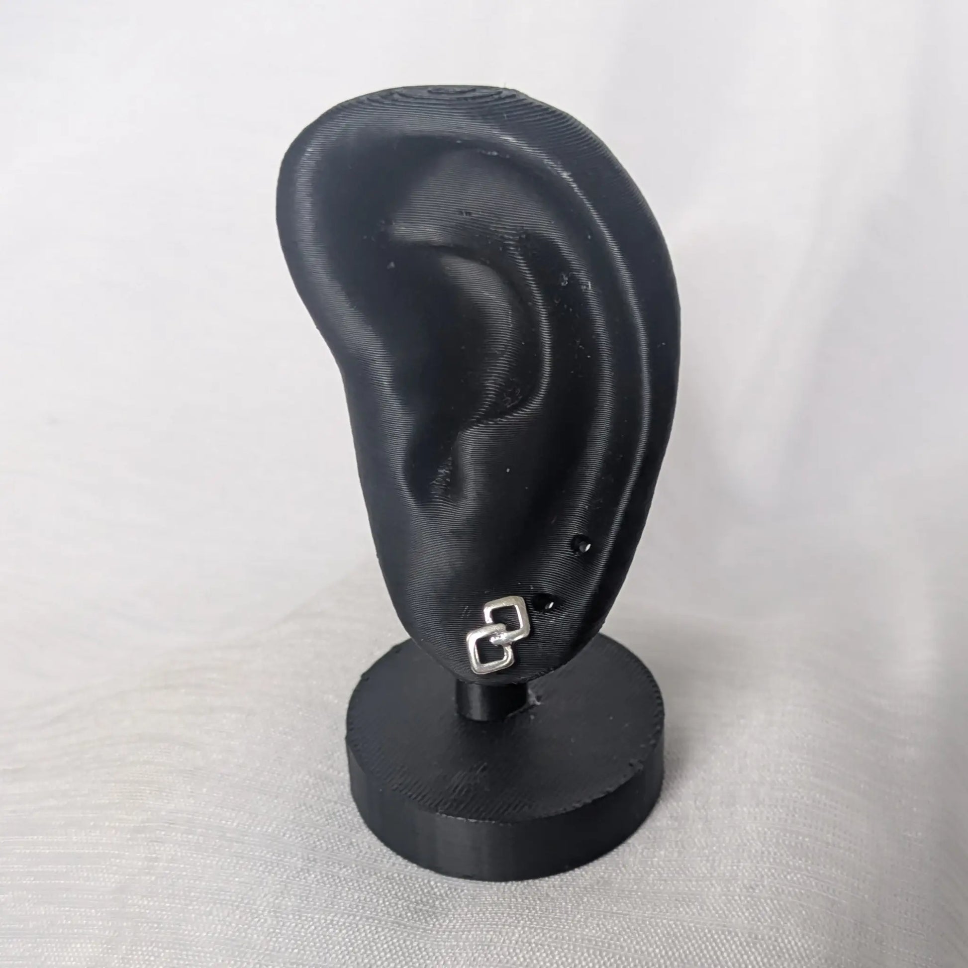 Geometrische Doppel-Rauten Ohrstecker an einem schwarzen Schmuck-Display zur Darstellung der Größe am Ohr.