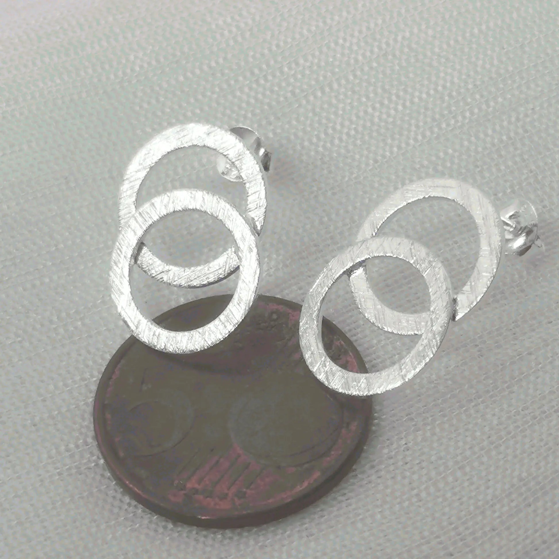 Größenvergleich der modernen, matten Kreis-Ohrringe aus 925 Silber platziert auf einer 5-Cent-Münze für eine reale Größenübersicht.