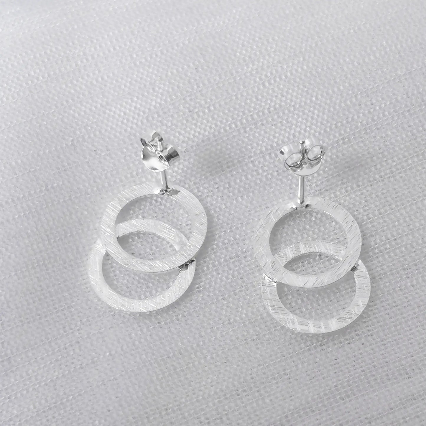 Rückansicht der silbernen Zwei-Ring-Ohrstecker zur Darstellung der Ohrstift-Verarbeitung und der matten Materialbeschaffenheit.