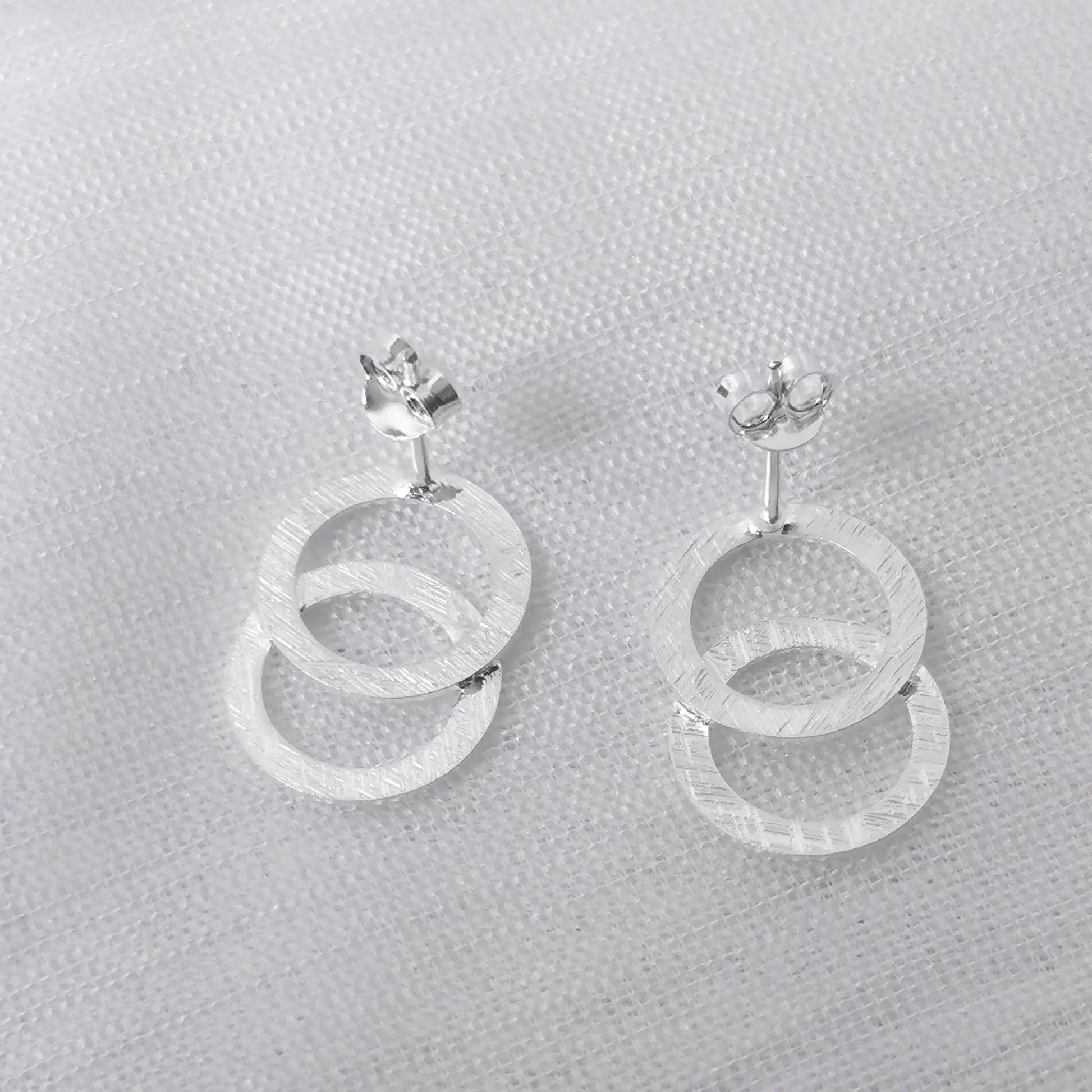 Rückansicht der silbernen Zwei-Ring-Ohrstecker zur Darstellung der Ohrstift-Verarbeitung und der matten Materialbeschaffenheit.