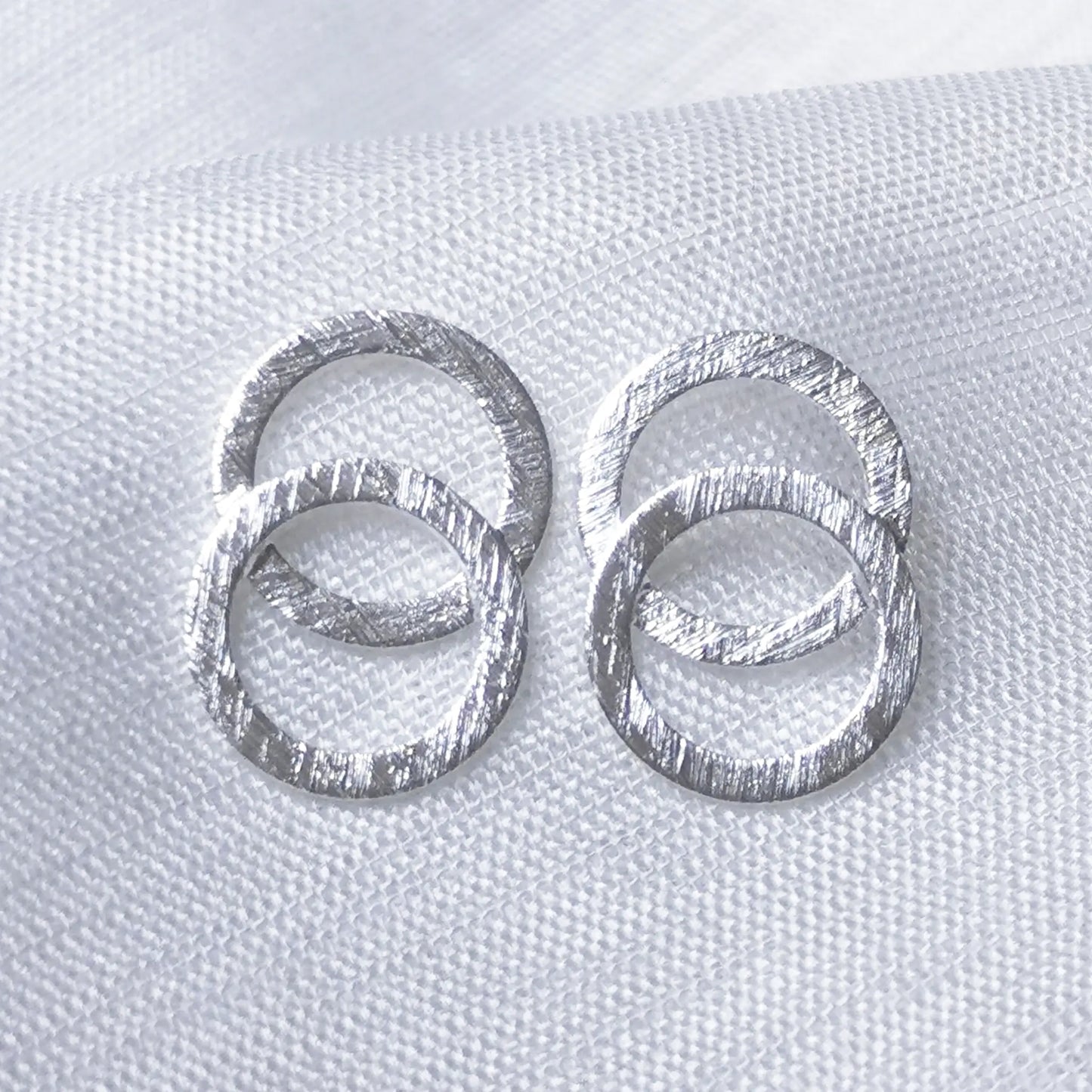 Nahaufnahme von geometrischen Doppelkreis-Ohrsteckern aus 925 Silber mit stark gebürsteter Oberfläche im matten Eiskratz-Look