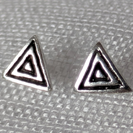 Frontalansicht der geometrischen Dreieck-Ohrstecker aus Silber mit dunklen Antik-Akzenten auf hellem Stoff.