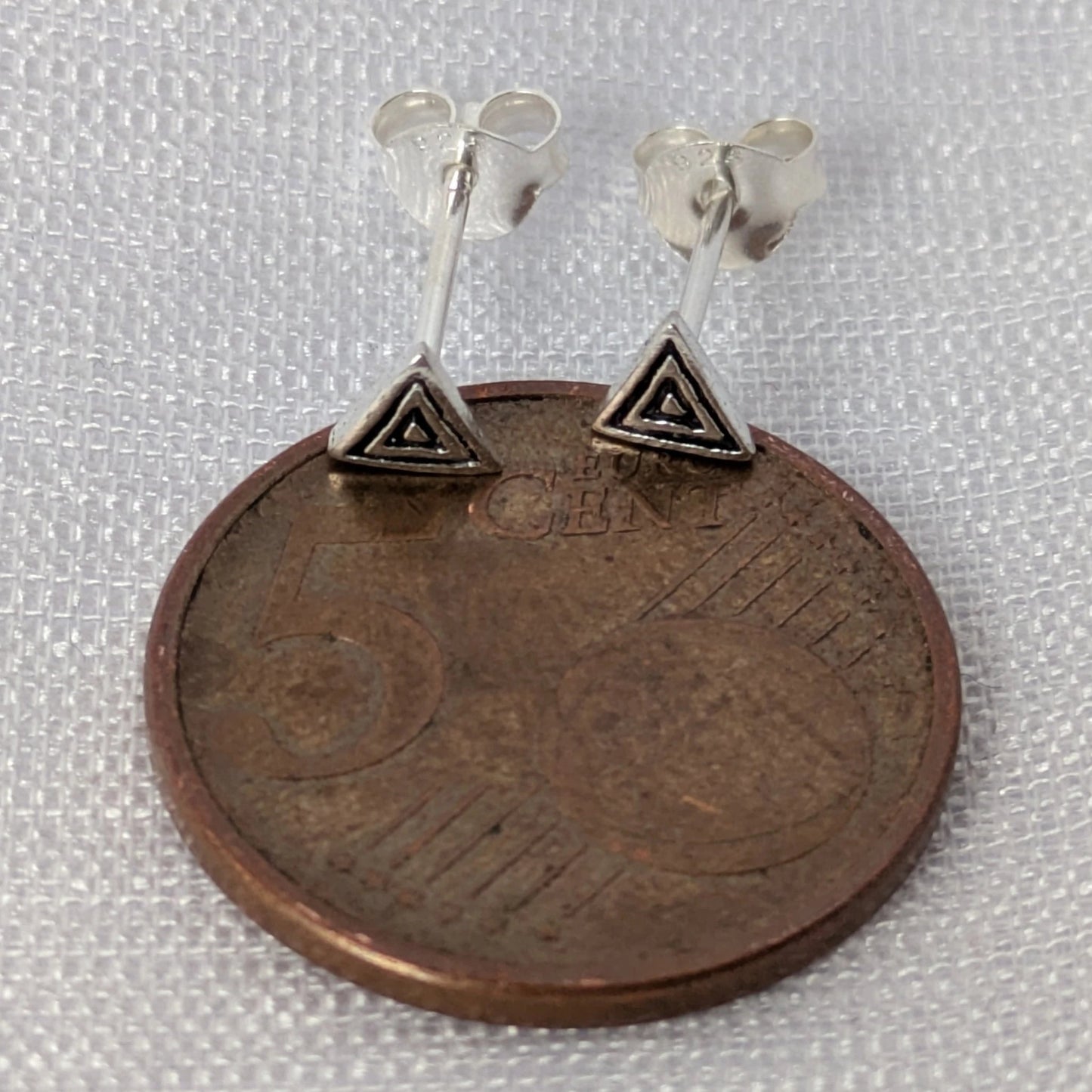 Größenvergleich der geometrischen Silber-Ohrstecker auf einer 5-Cent-Münze liegend.