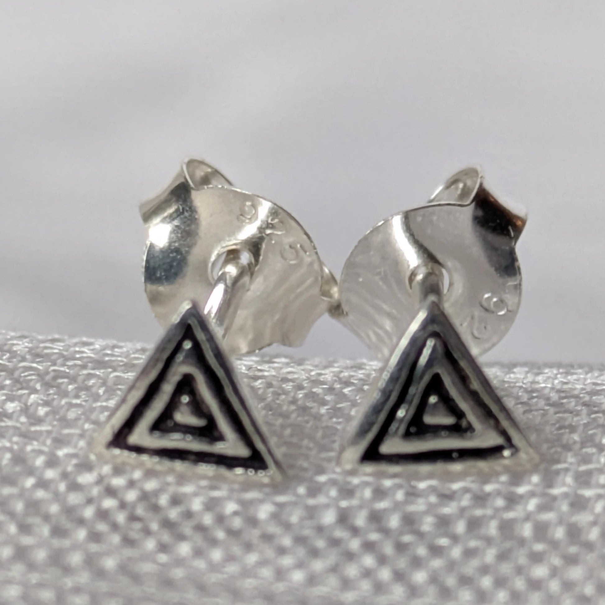 Paar strukturierte Dreieck-Ohrstecker aus 925 Sterling Silber, freigestellt für eine detaillierte Produktansicht.