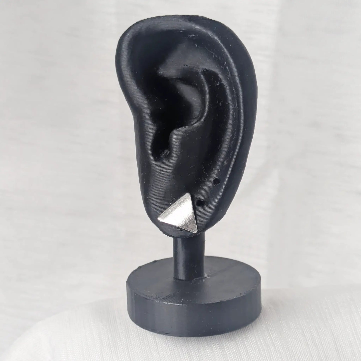 Kontrastreiche Präsentation der silbernen Ohrstecker auf schwarzem Schmuckdisplay.