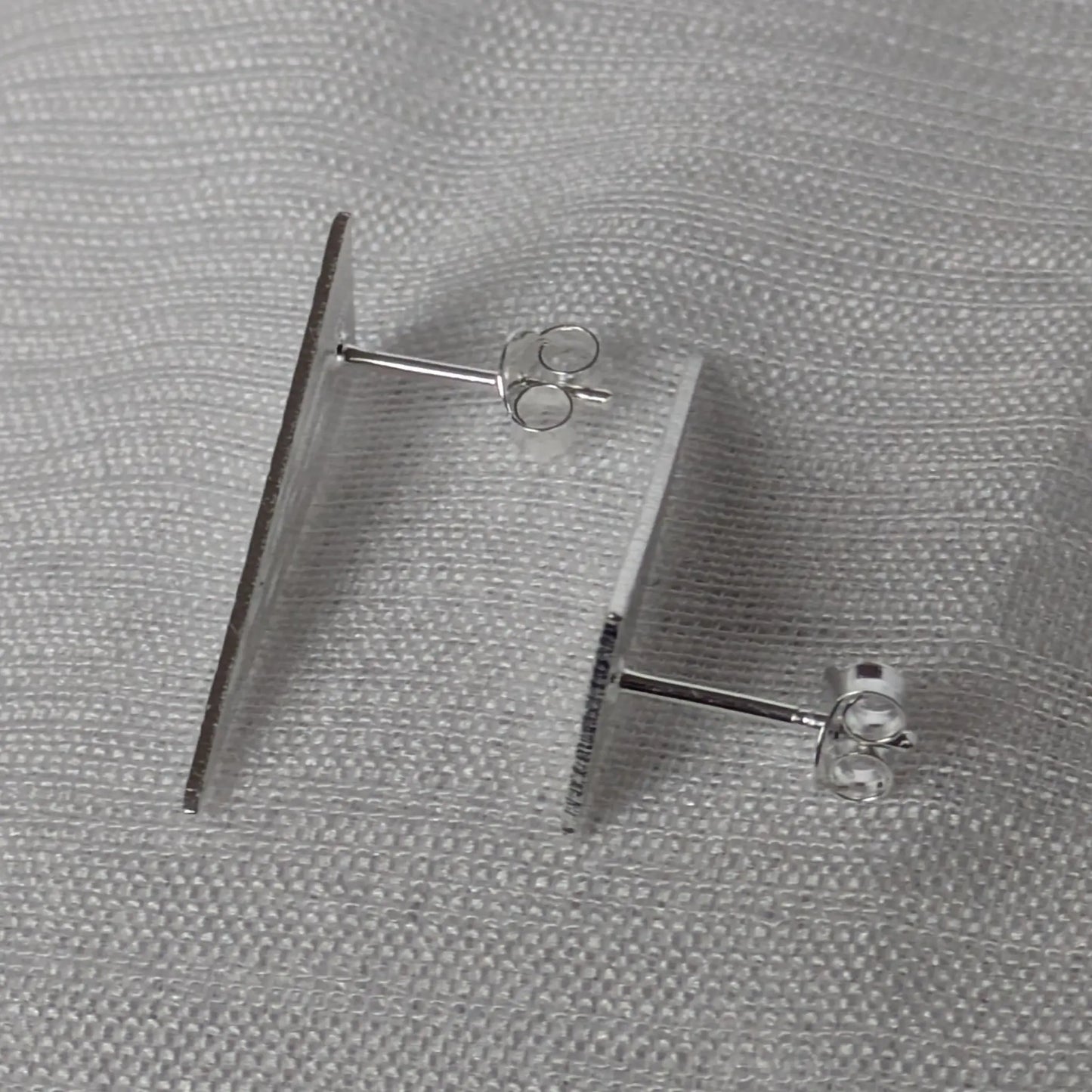Seitenansicht der flachen silbernen Dreieck-Ohrstecker mit sicherem Verschluss.