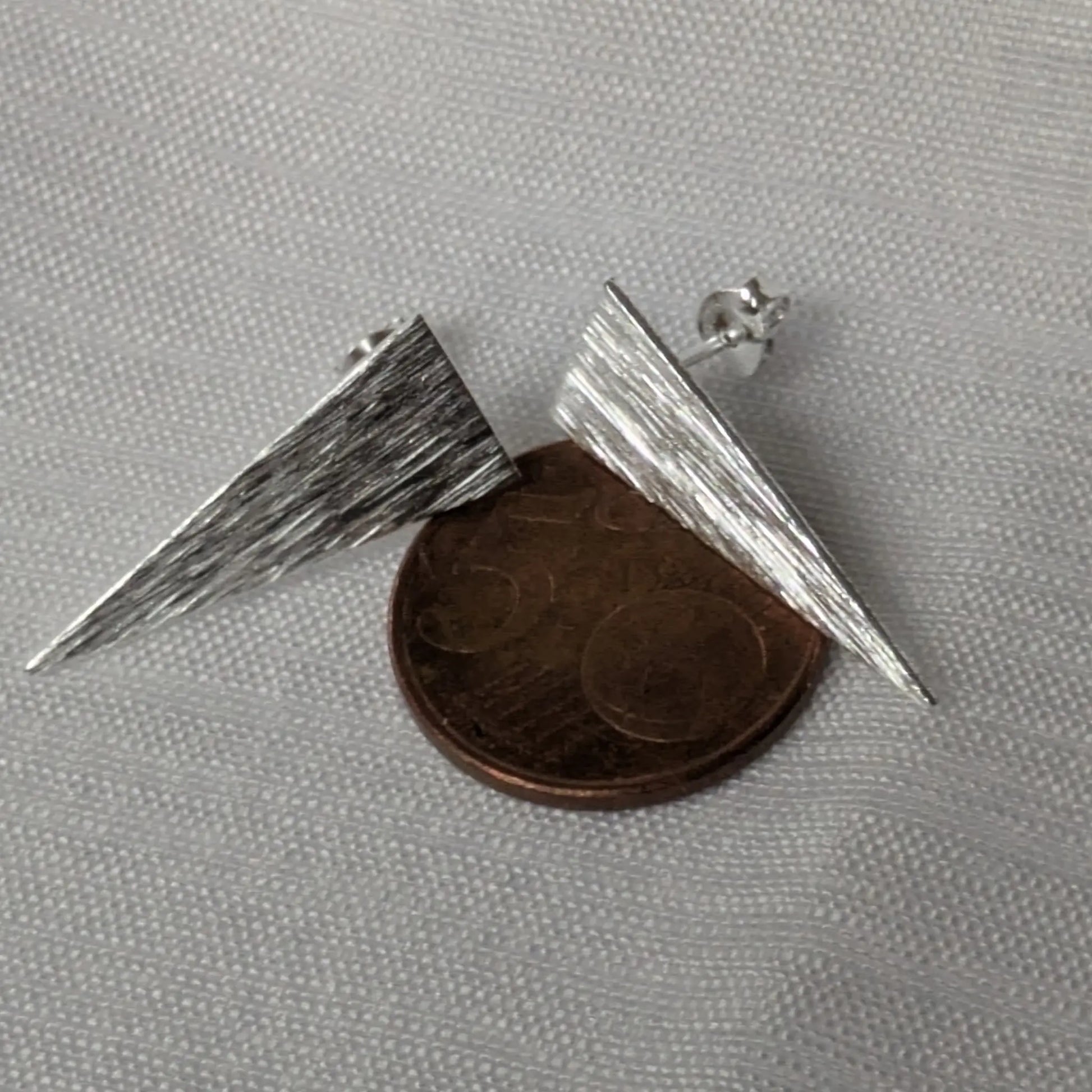 Größenvergleich der langen Dreieck-Ohrstecker neben einer 5-Cent-Münze.