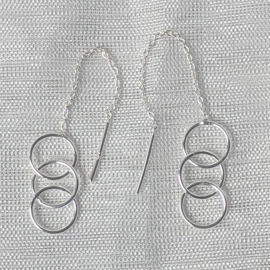 Nahaufnahme der 925 Silber Durchzieher-Ohrringe, die die zarte Gliederkette und die drei polierten, ineinander hängenden Kreise zeigt.