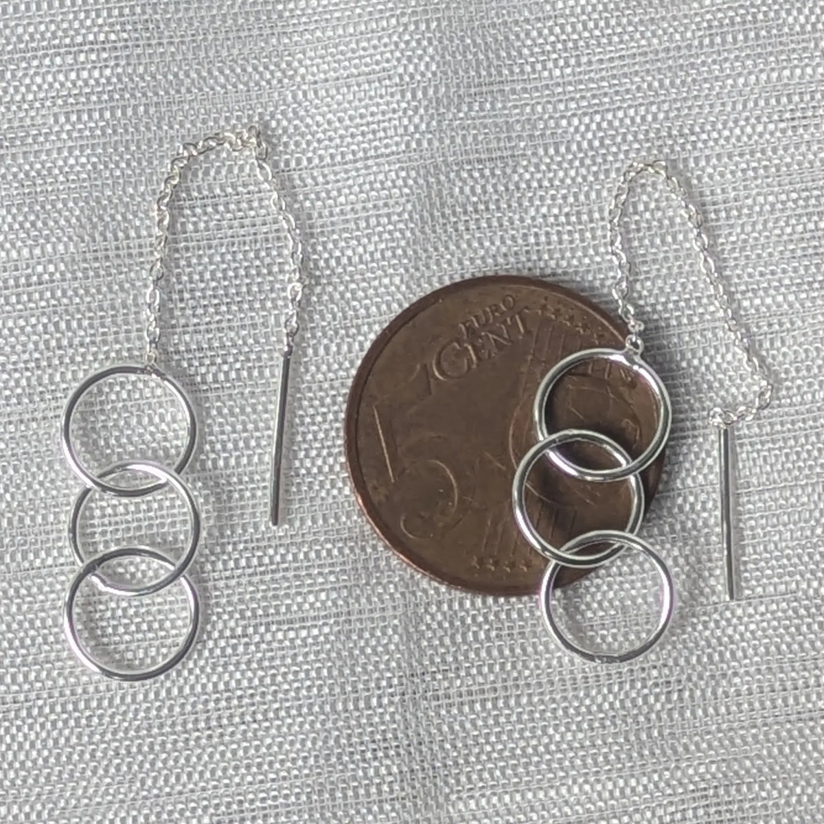 Größenvergleich: Die feinen Silber-Durchzieher mit den drei Kreisen liegen flach auf einer 5-Cent-Münze.