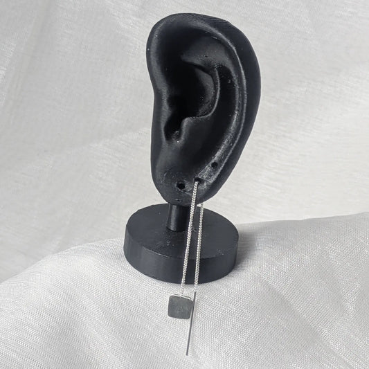 Zarter Durchzieher-Ohrring aus Silber, getragen an einem schwarzen Ohr-Display zur Veranschaulichung des eleganten Falls am Ohr.
