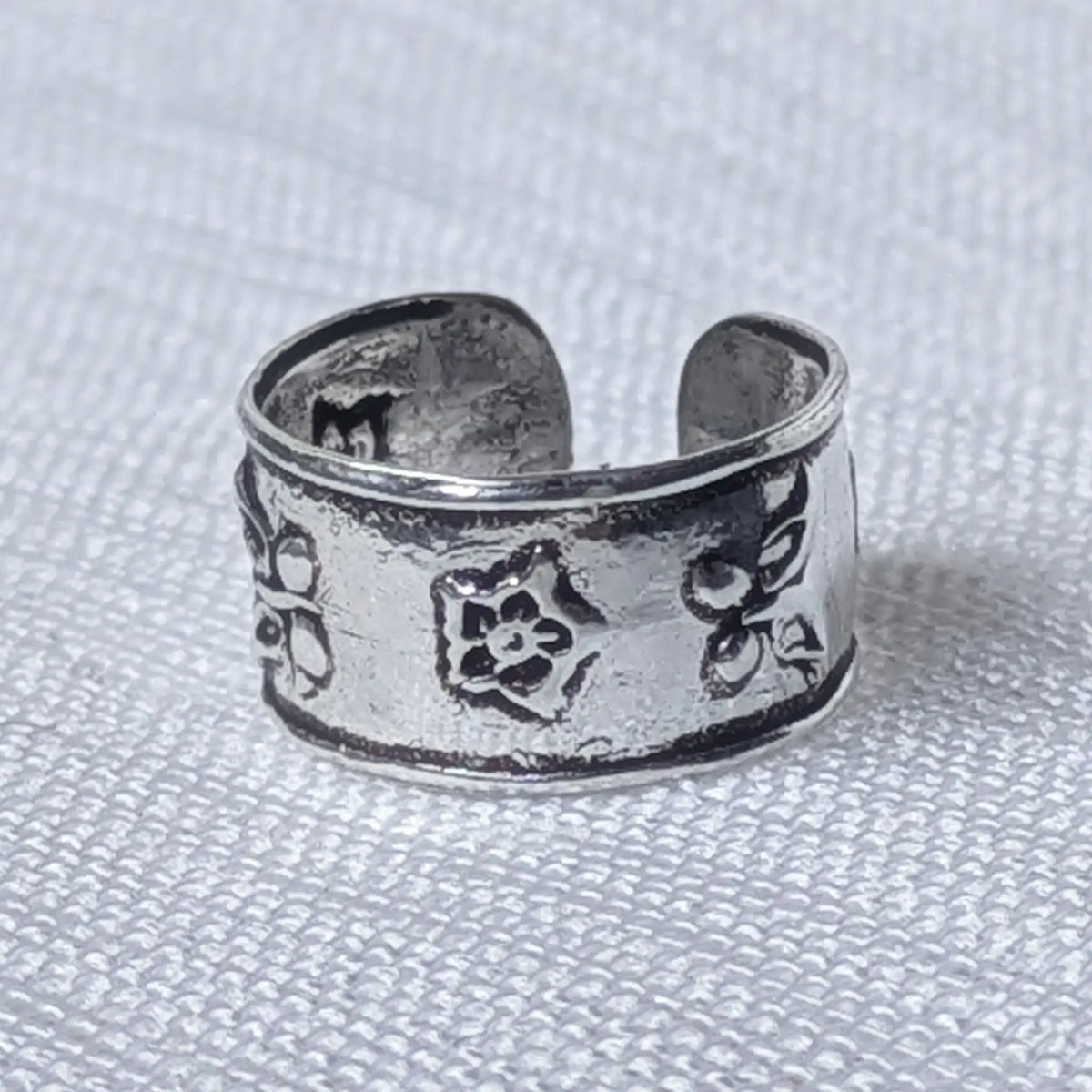 Nahaufnahme einer breiten Ohrklemme aus 925 Silber mit geprägtem Vintage Blumenmuster.