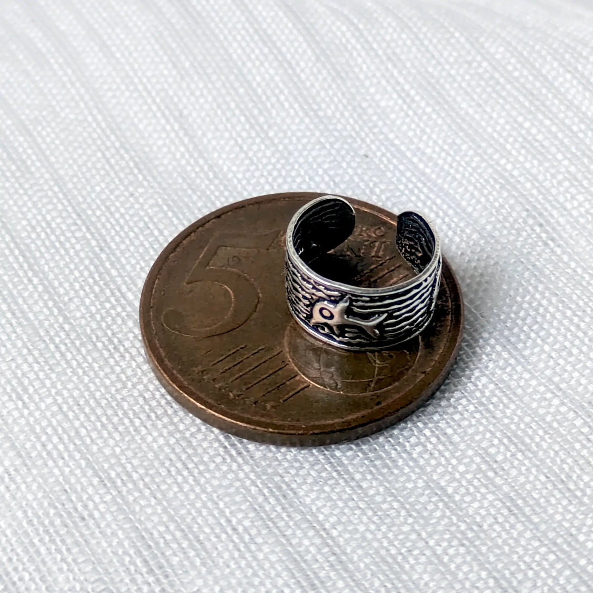 Größenvergleich: Maritimer 925 Silber Ear Cuff mit Delfin-Muster liegt auf einer 5-Cent-Münze.
