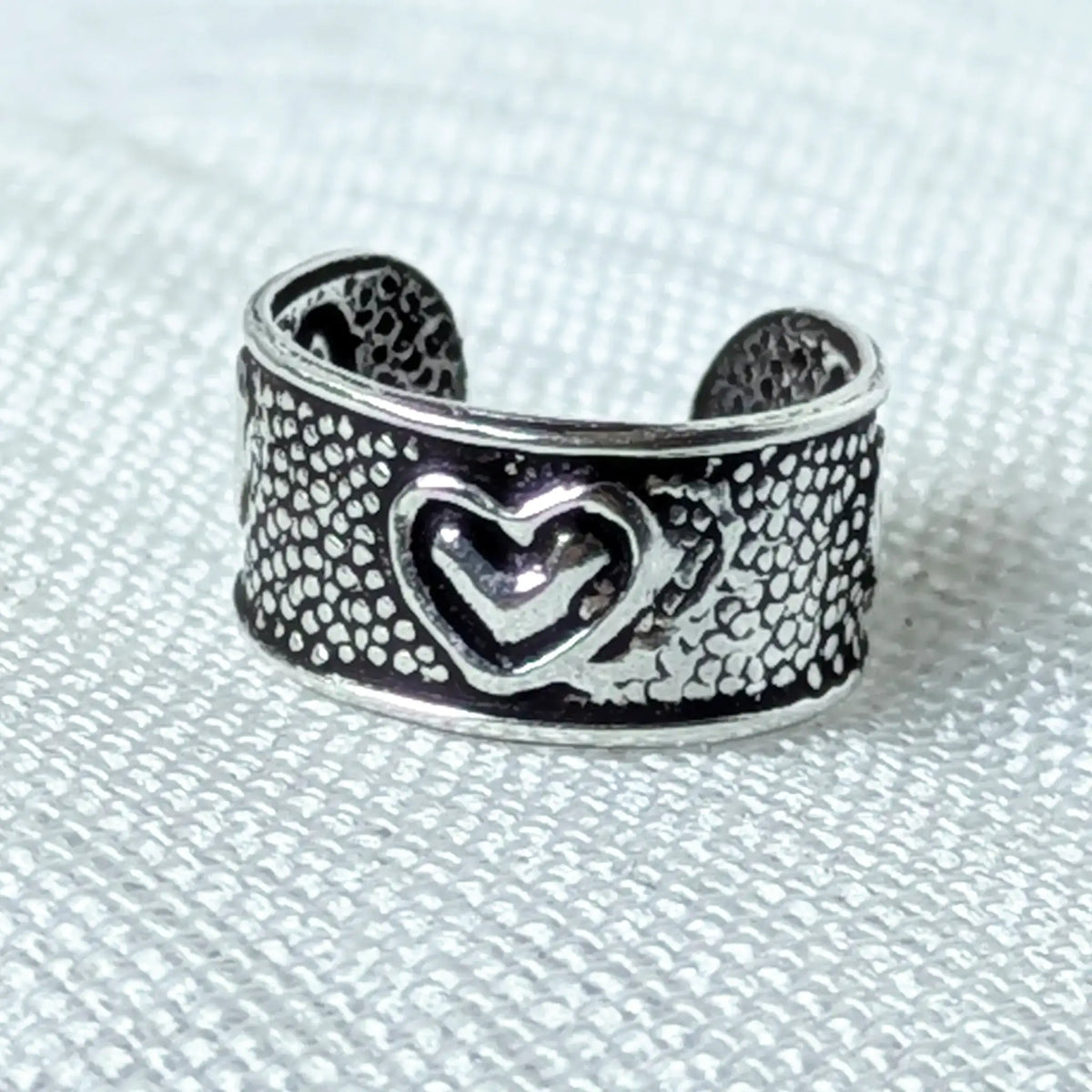 Nahaufnahme eines 925 Silber Ear Cuffs mit Herz-Motiv und geschwärzter Vintage-Struktur.