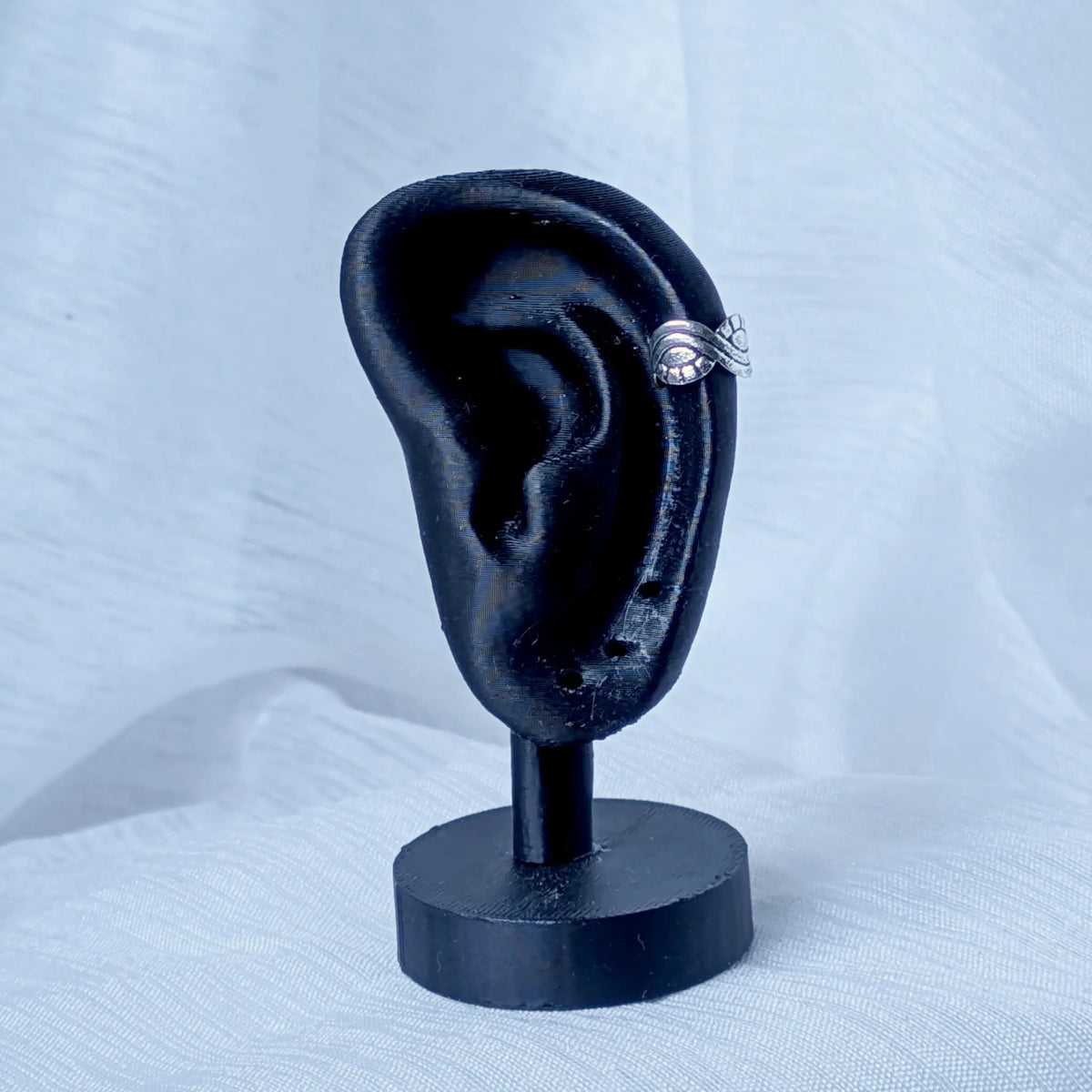 Die silberne Ohrklemme stilvoll platziert an der äußeren Kante eines schwarzen 3D-Ohr-Displays.
