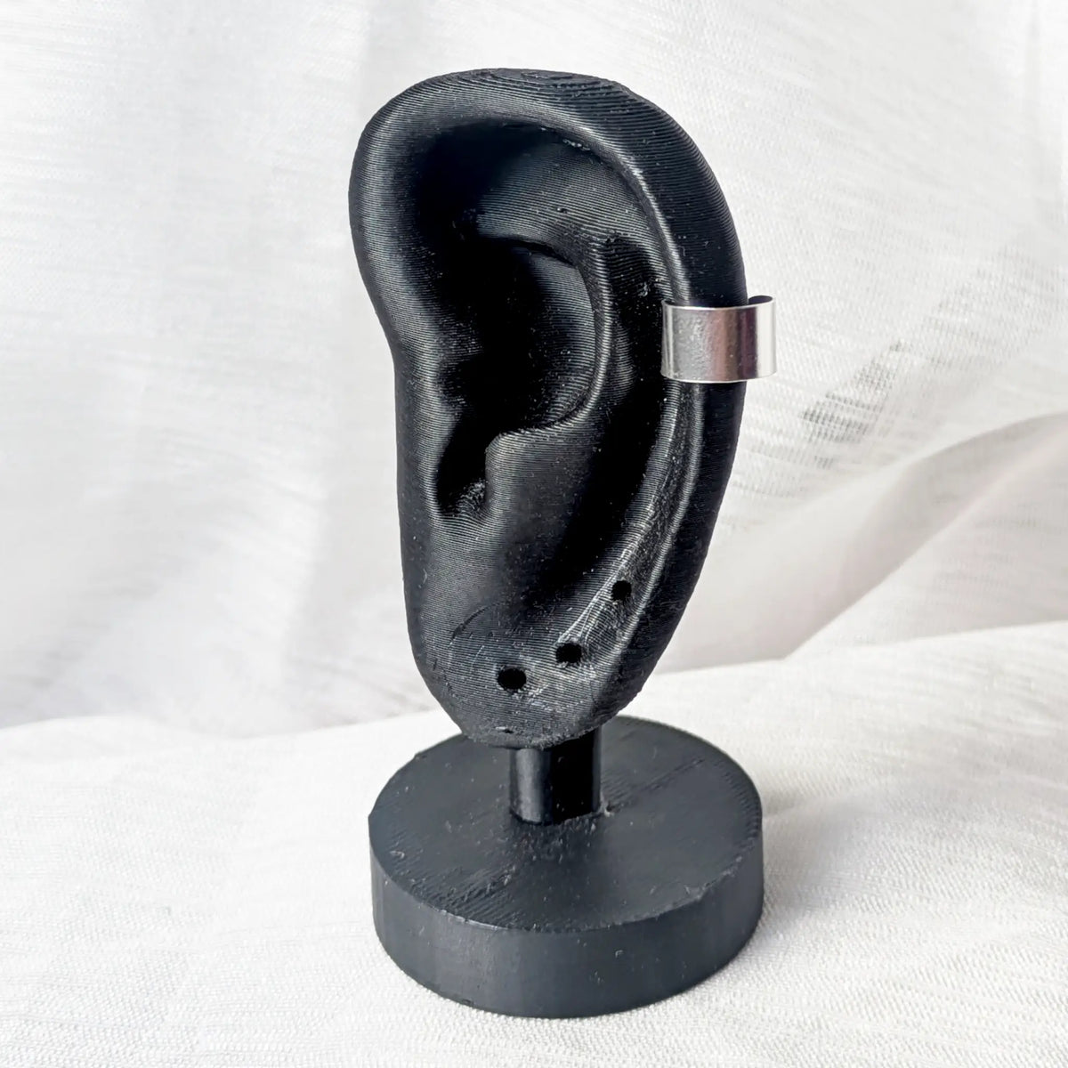 Breiter Silber Ear Cuff, getragen am äußeren Knorpel eines schwarzen 3D-Modell-Ohrs.