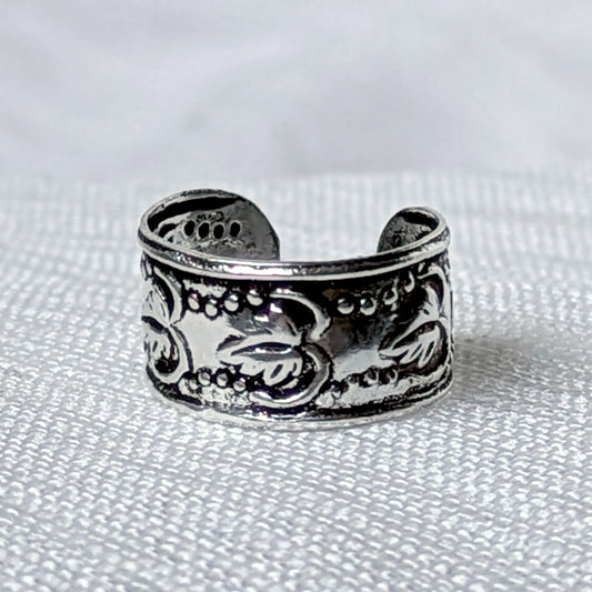 Nahaufnahme einer breiten Ohrklemme aus 925 Silber mit geprägtem Vintage Blätter- und Rankenmuster auf geschwärztem Grund.