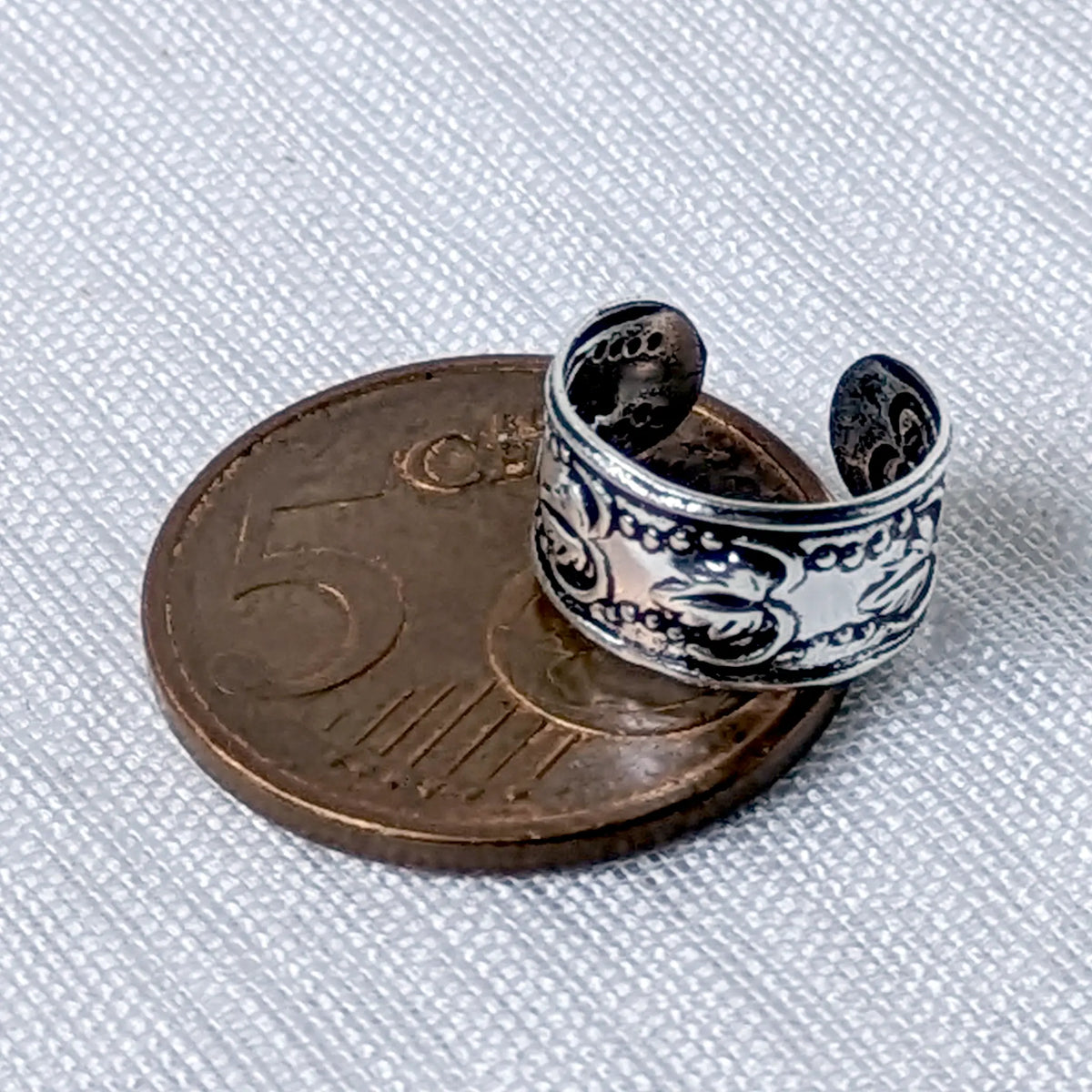 Größenvergleich der breiten 925 Silber Ohrklemme mit floralem Boho-Muster, direkt platziert auf einer 5-Cent-Münze.