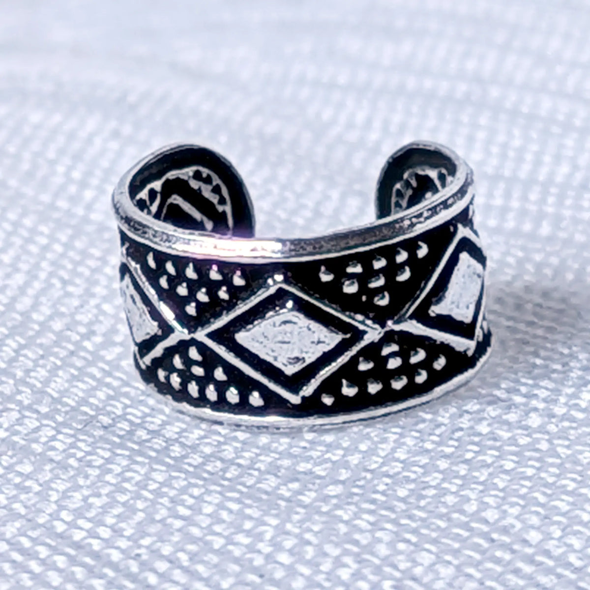 Nahaufnahme eines silbernen Ear Cuffs aus 925 Silber mit geschwärztem Ethno-Rautenmuster.