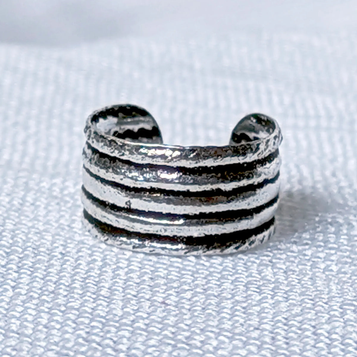 Nahaufnahme eines mehrreihigen Ear Cuffs aus 925 Silber mit gehämmerter Vintage-Struktur.
