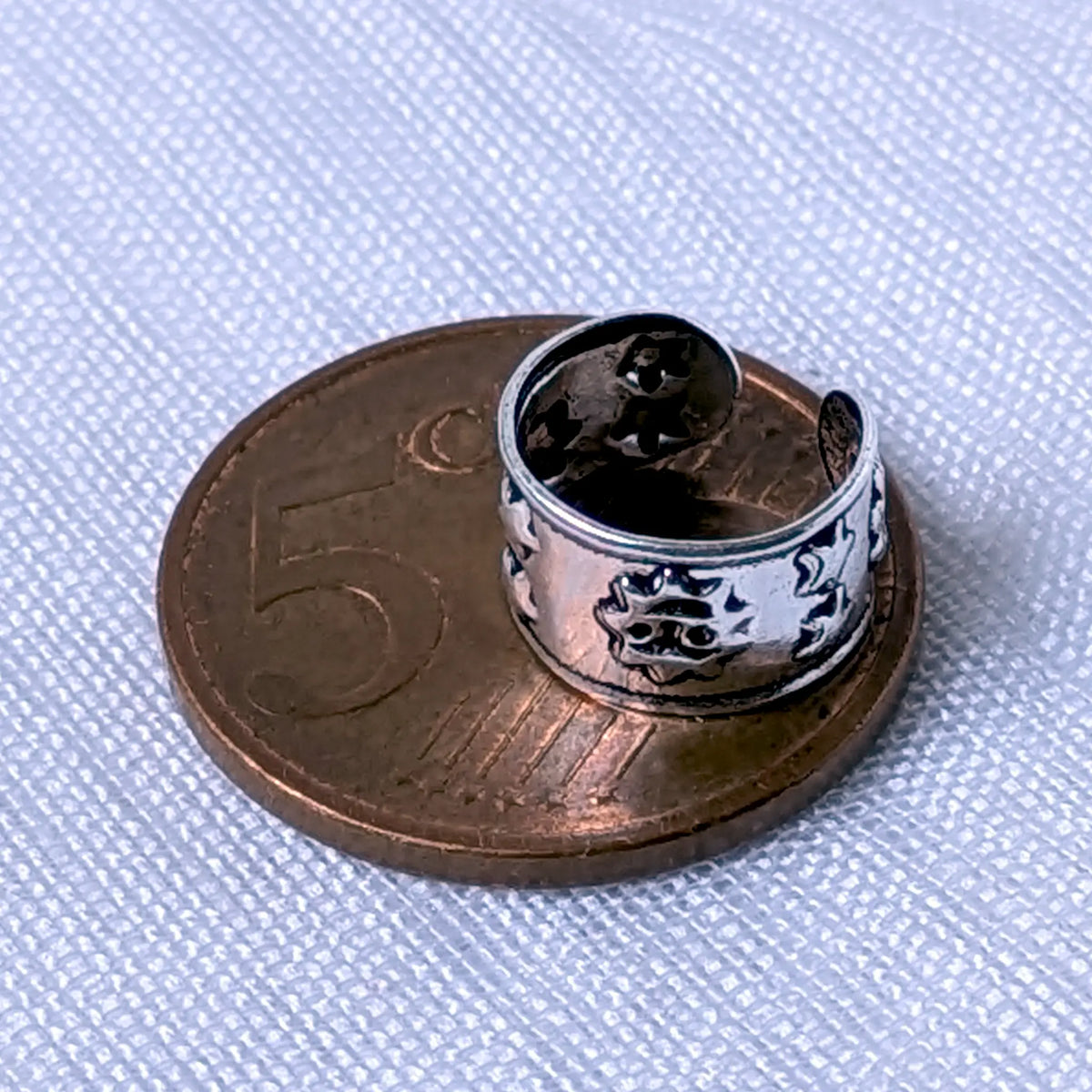 Größenvergleich: Die 925 Silber Ohrklemme mit dem Sonne-Sterne-Design liegt flach auf einer 5-Cent-Münze.