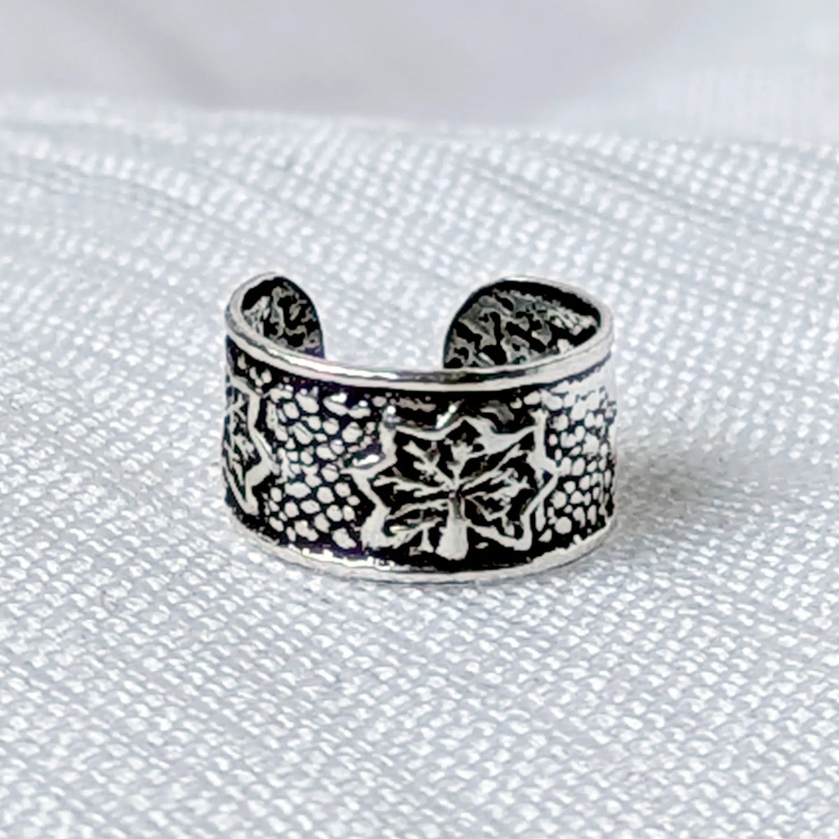 Nahaufnahme eines breiten Ear Cuffs aus 925 Silber mit detailliertem Blüten-Muster und strukturierter Vintage-Oberfläche.