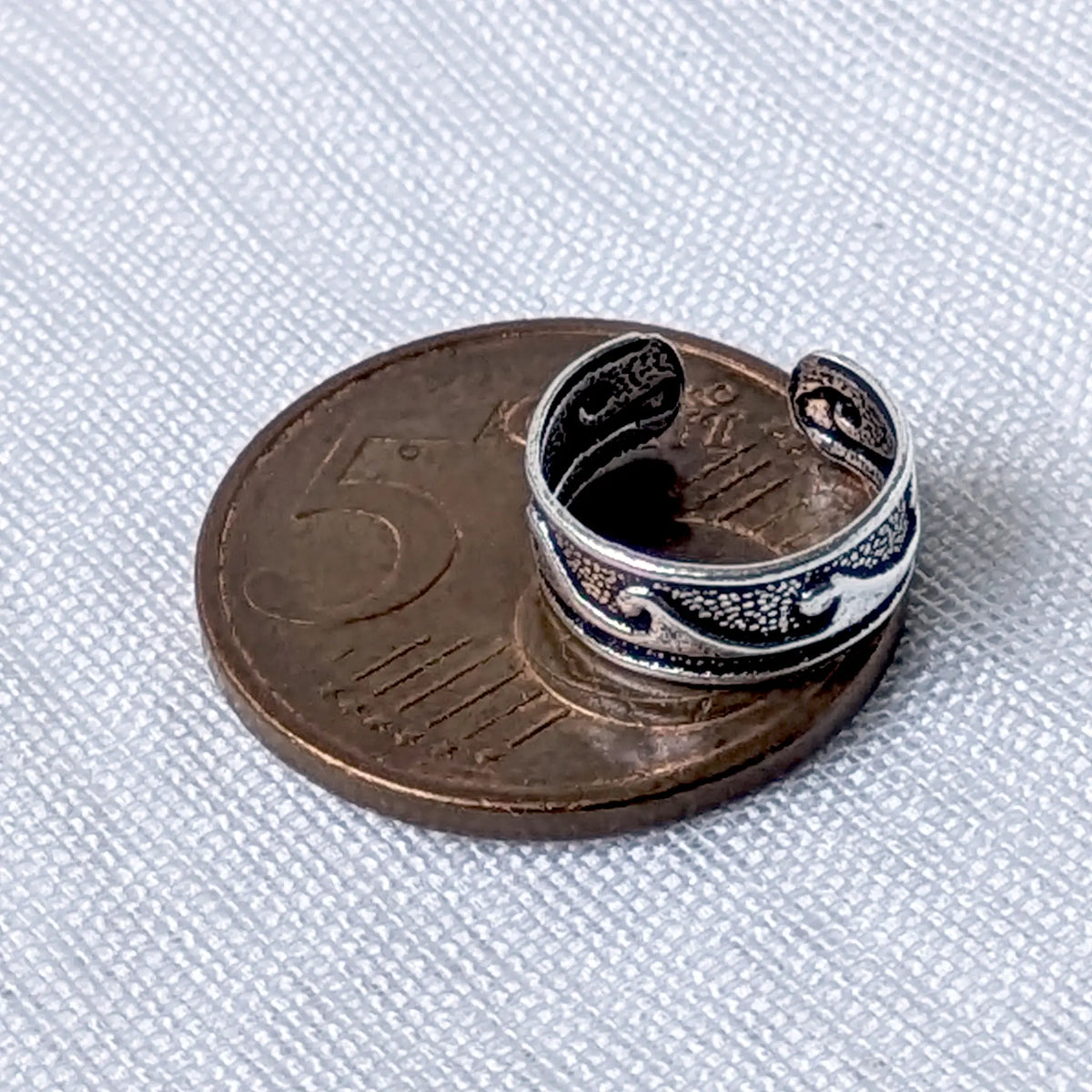 Silberner Vintage Ear Cuff mit Wellen-Muster liegt zum direkten Größenvergleich auf einer 5-Cent-Münze.