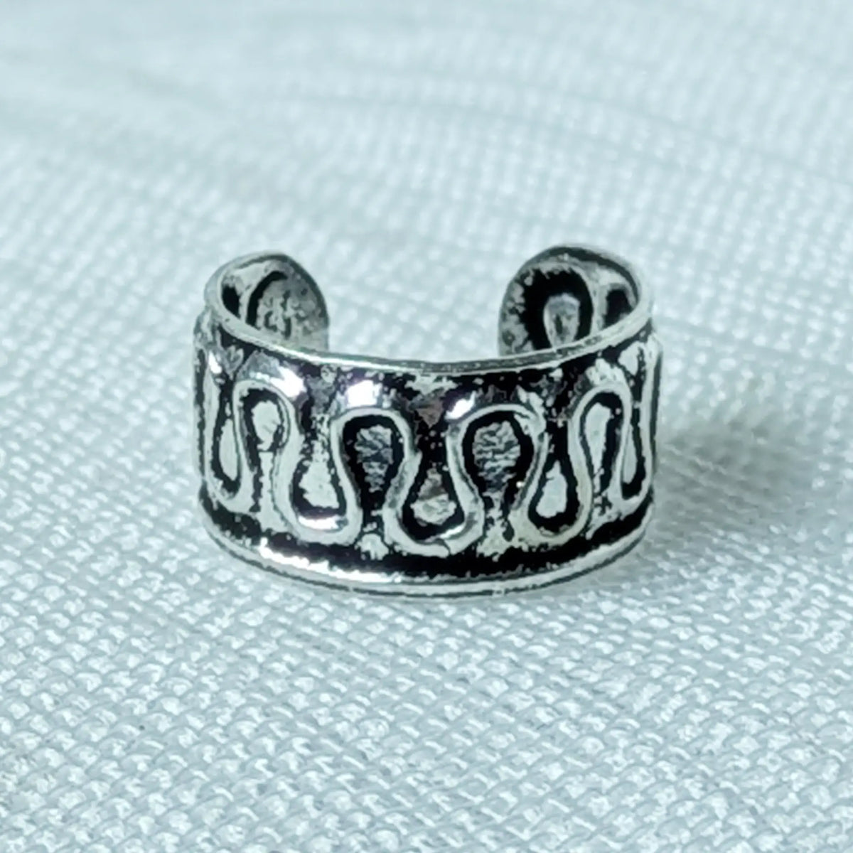 Nahaufnahme einer 925 Silber Ohrklemme mit durchbrochenem Wellen-Muster und geschwärztem Hintergrund.