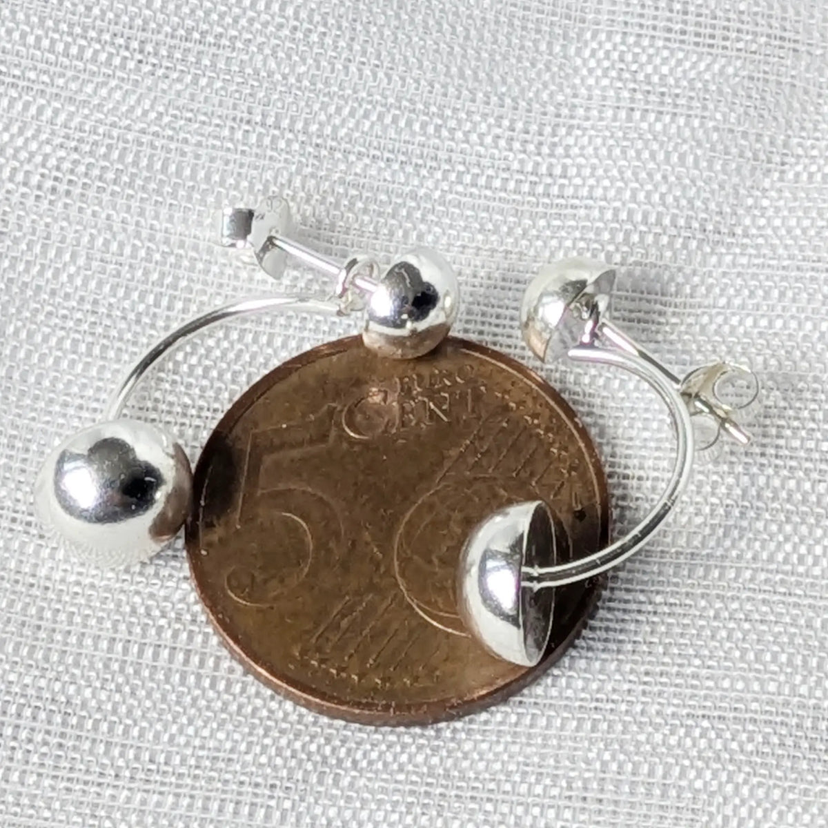Doppel-Kugel Silber-Ohrstecker liegend auf einer 5-Cent-Münze zum genauen Größenvergleich.