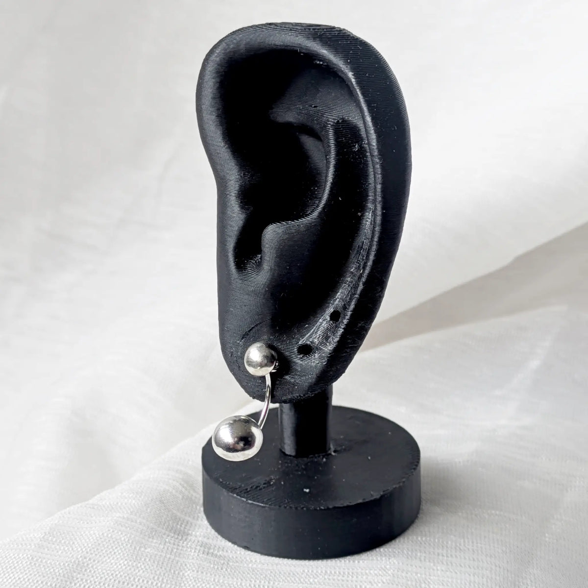 Silberne Ear Jackets stilvoll präsentiert am Ohrläppchen eines schwarzen Ohr-Displays.