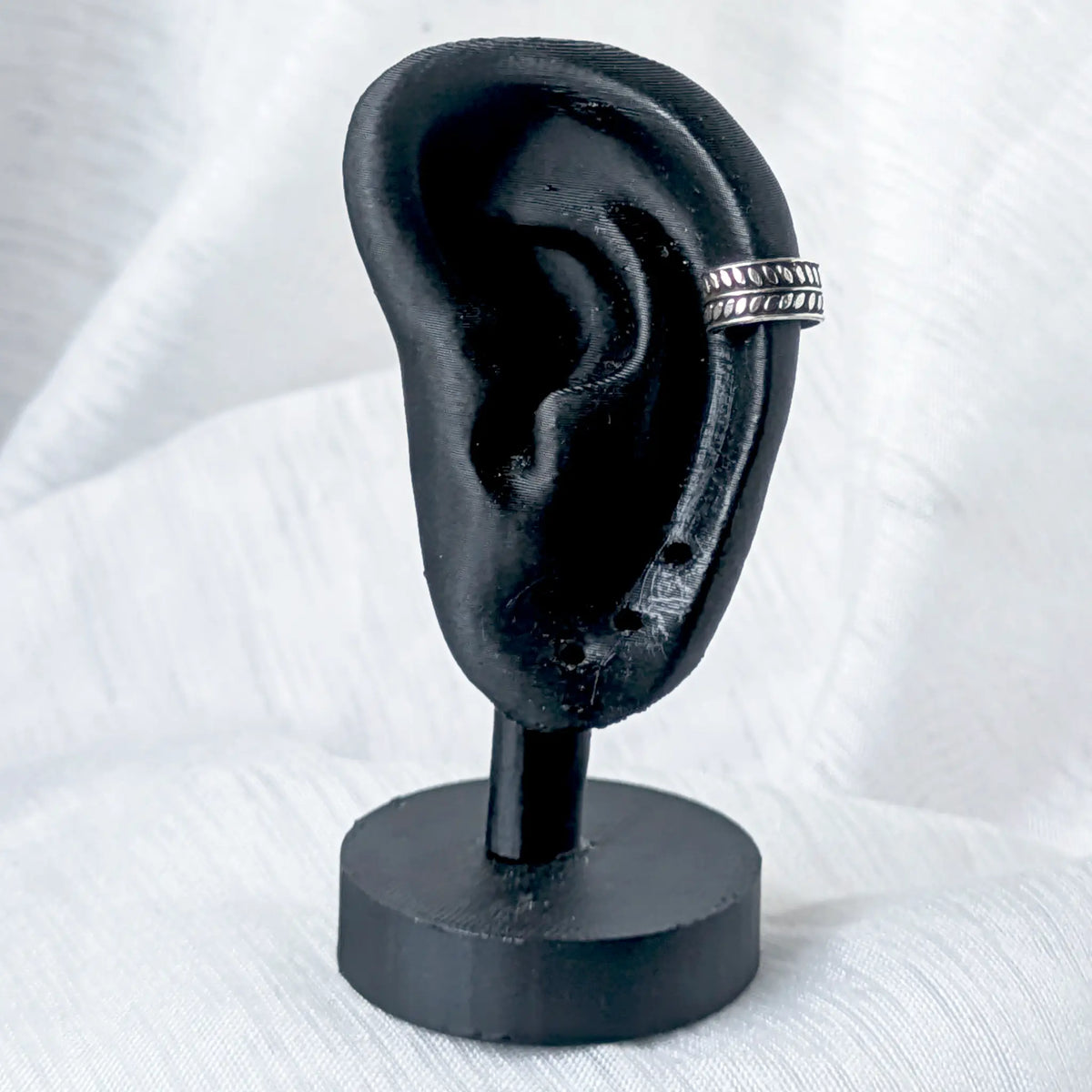 Zweireihige Silber-Ohrklemme mit Ährenmuster, stilvoll getragen am oberen Knorpel (Helix) eines schwarzen 3D-Ohr-Displays.