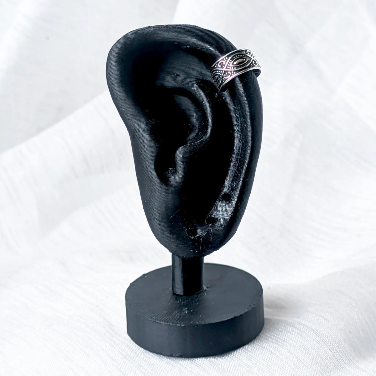 Silberne Ohrklemme mit Augen-Design, stilvoll getragen am oberen Helix-Knorpel eines schwarzen 3D-Ohr-Displays.