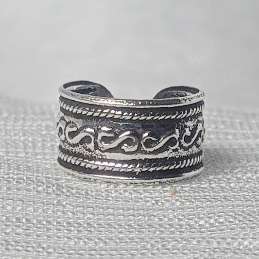 Nahaufnahme einer breiten Ohrklemme aus 925 Silber mit S-Wellenmuster und Kordelrand auf geschwärztem Grund.
