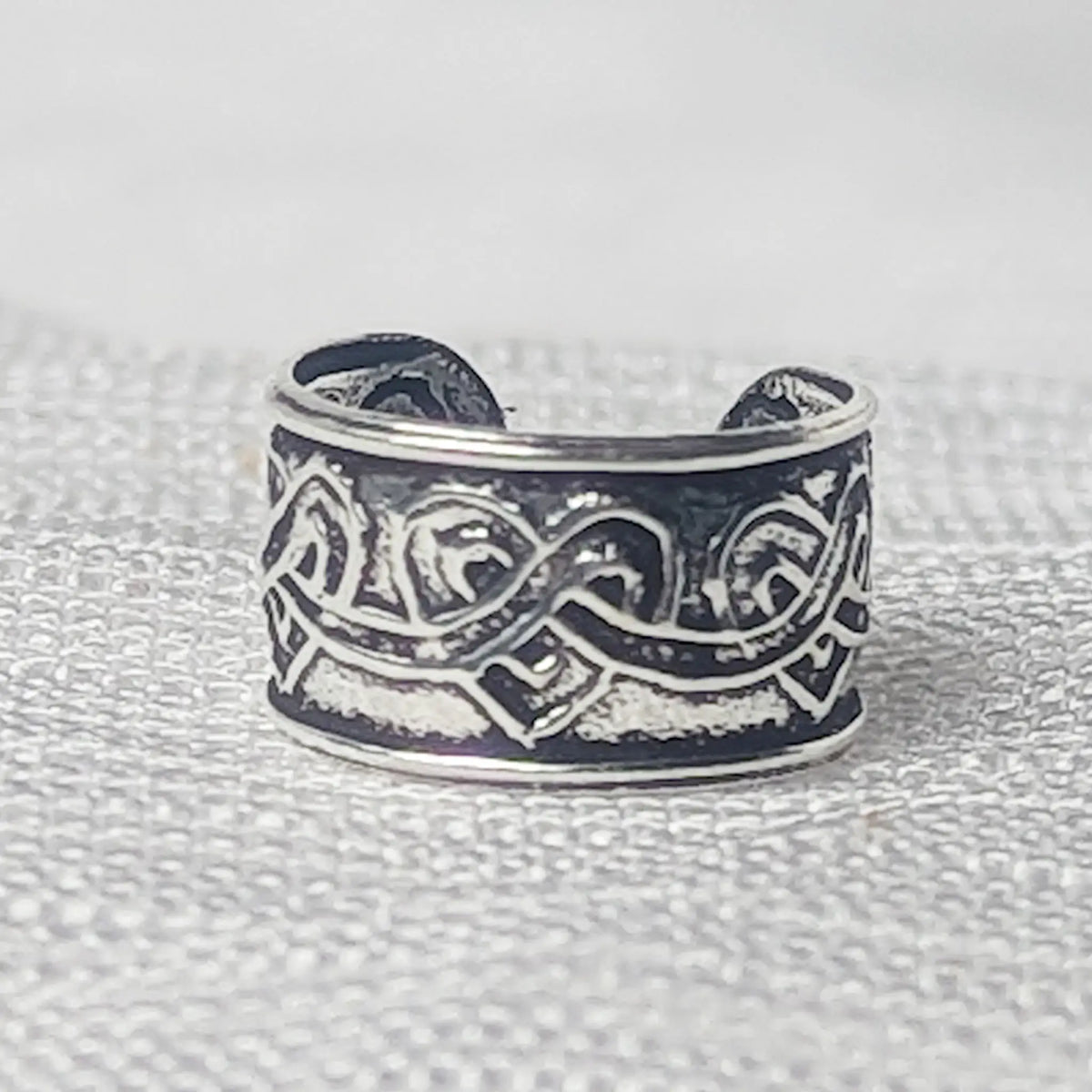 Nahaufnahme einer 925 Silber Ohrklemme mit Herzmuster und geschwärztem Hintergrund.