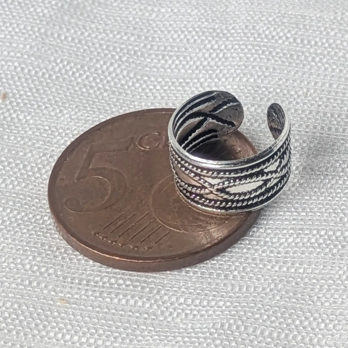 Größenvergleich: Die silberne Ohrklemme mit Vintage-Kordelmuster liegt flach auf einer 5-Cent-Münze.