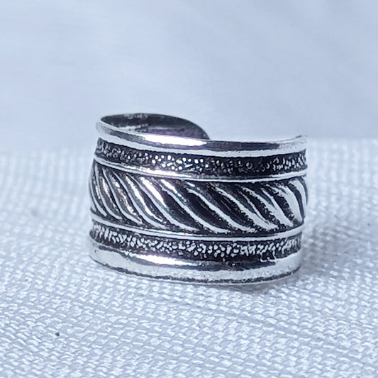 Nahaufnahme einer breiten Ohrklemme aus 925 Silber mit zentralem Kordelmuster und strukturierten Rändern auf geschwärztem Grund.