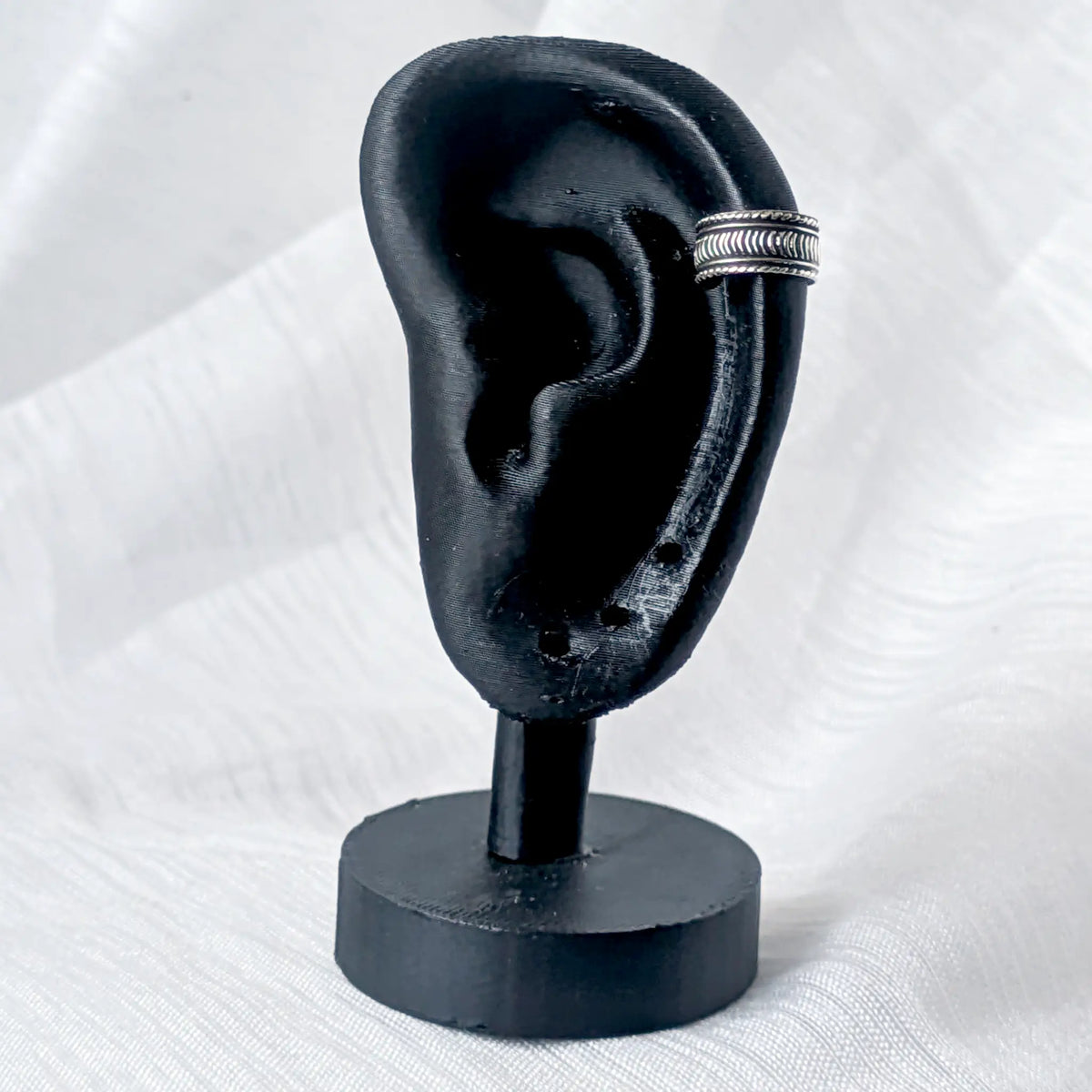 Silberne Ohrklemme im Tribal-Design, stilvoll getragen am äußeren Helix-Knorpel eines schwarzen 3D-Ohr-Displays.