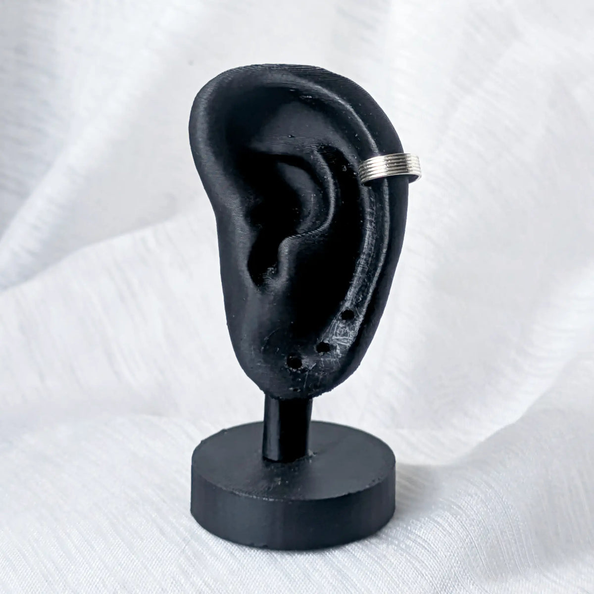 Minimalistische 925 Silber Ohrklemme mit Rillen-Design, getragen am äußeren Knorpel eines schwarzen 3D-Ohr-Displays.