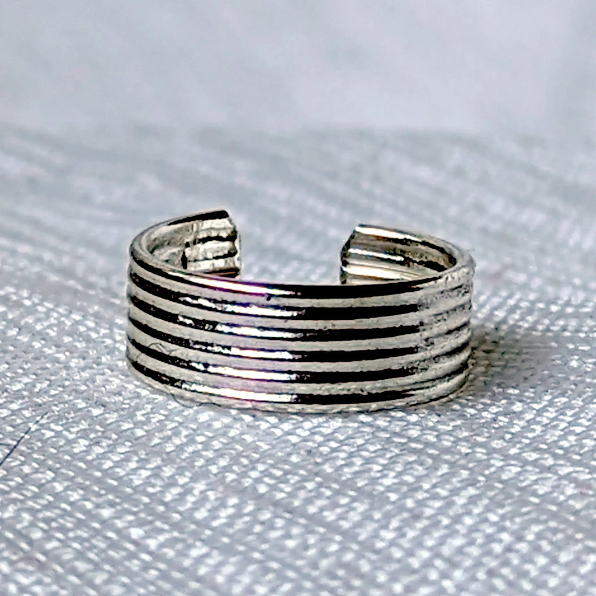 Nahaufnahme einer Ohrklemme aus 925 Silber mit minimalistischem, horizontalem Rillenmuster.