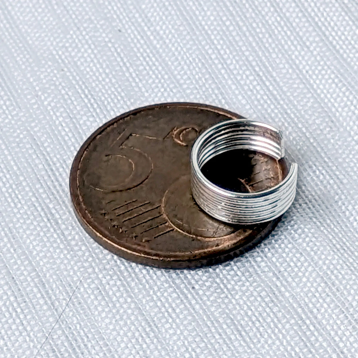 Größenvergleich der schlichten Silber-Ohrklemme mit Rillenmuster, zur Veranschaulichung auf einer 5-Cent-Münze platziert.