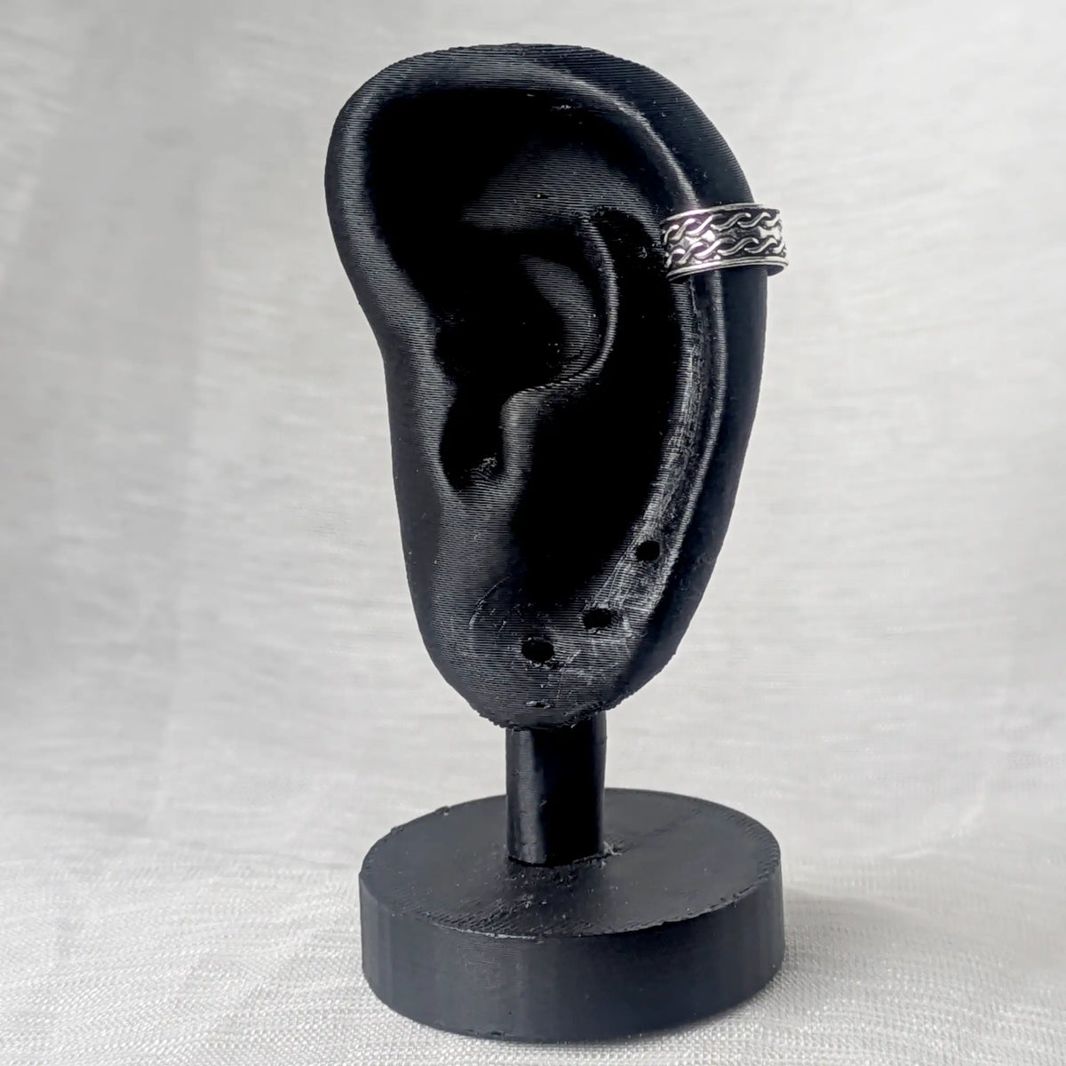 Silberne Ohrklemme mit Wellen-Muster, stilvoll getragen am äußeren Helix-Knorpel eines schwarzen 3D-Ohr-Displays.
