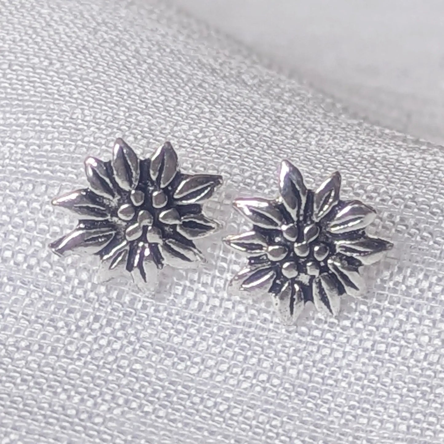 Detailreiche Nahaufnahme der Edelweiß Ohrstecker aus 925 Sterling Silber mit oxidierten Blütenblättern.