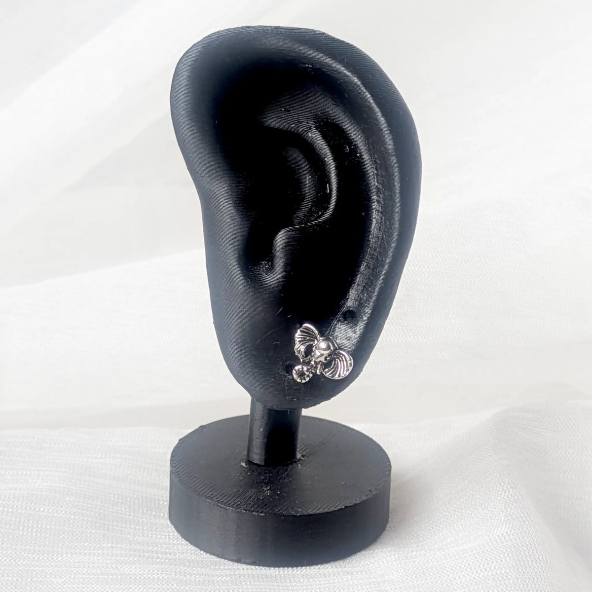 Ein silberner Elefanten-Ohrstecker präsentiert an einem schwarzen 3D-Ohr-Display zur Veranschaulichung der kompakten Größe.
