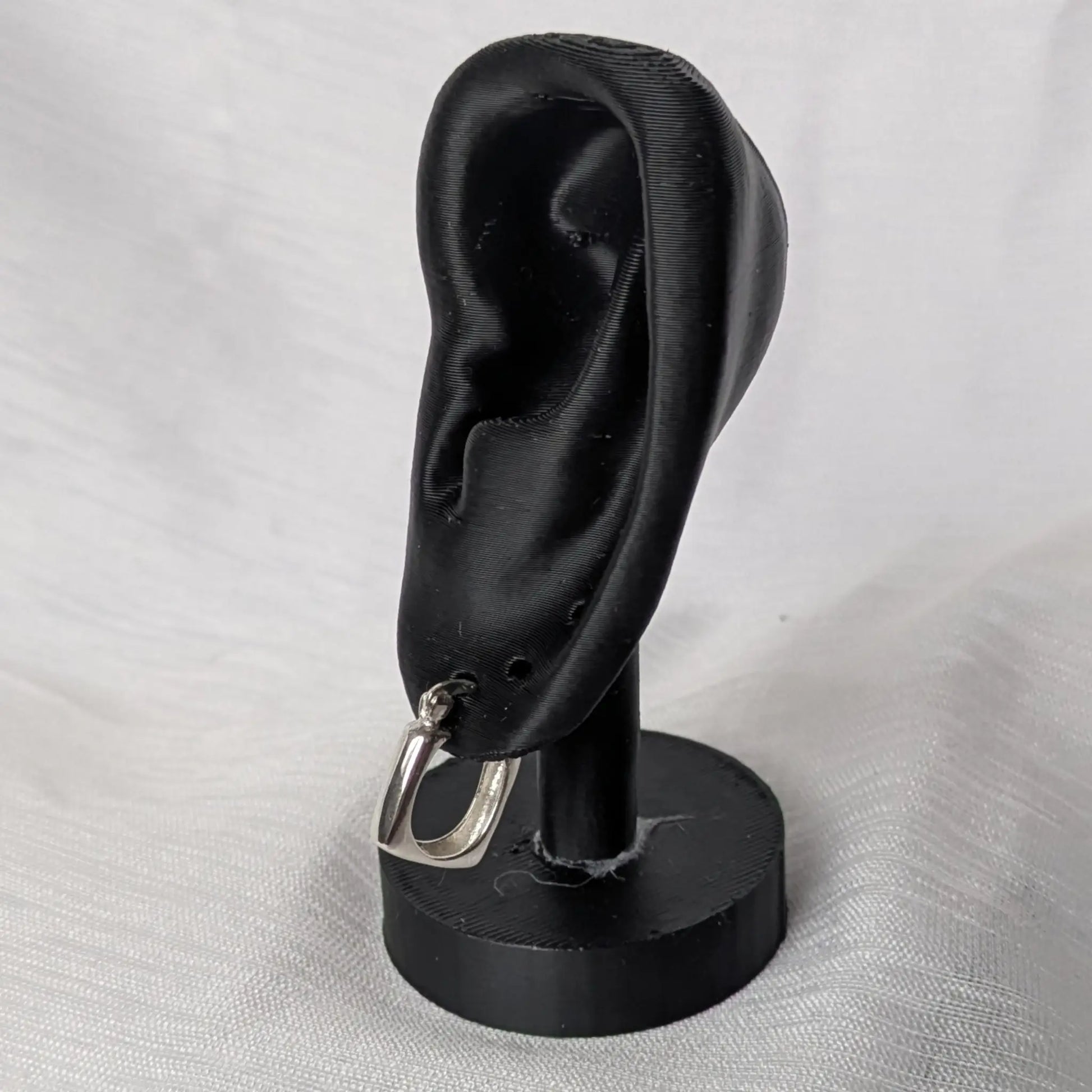Quadratische Silber-Ohrringe elegant präsentiert auf einem schwarzen Schmuckständer.