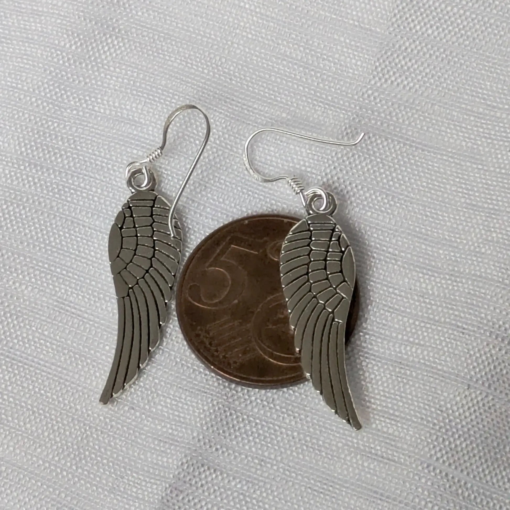 Größenvergleich der Flügel-Ohrringe platziert auf einer 5-Cent-Münze.