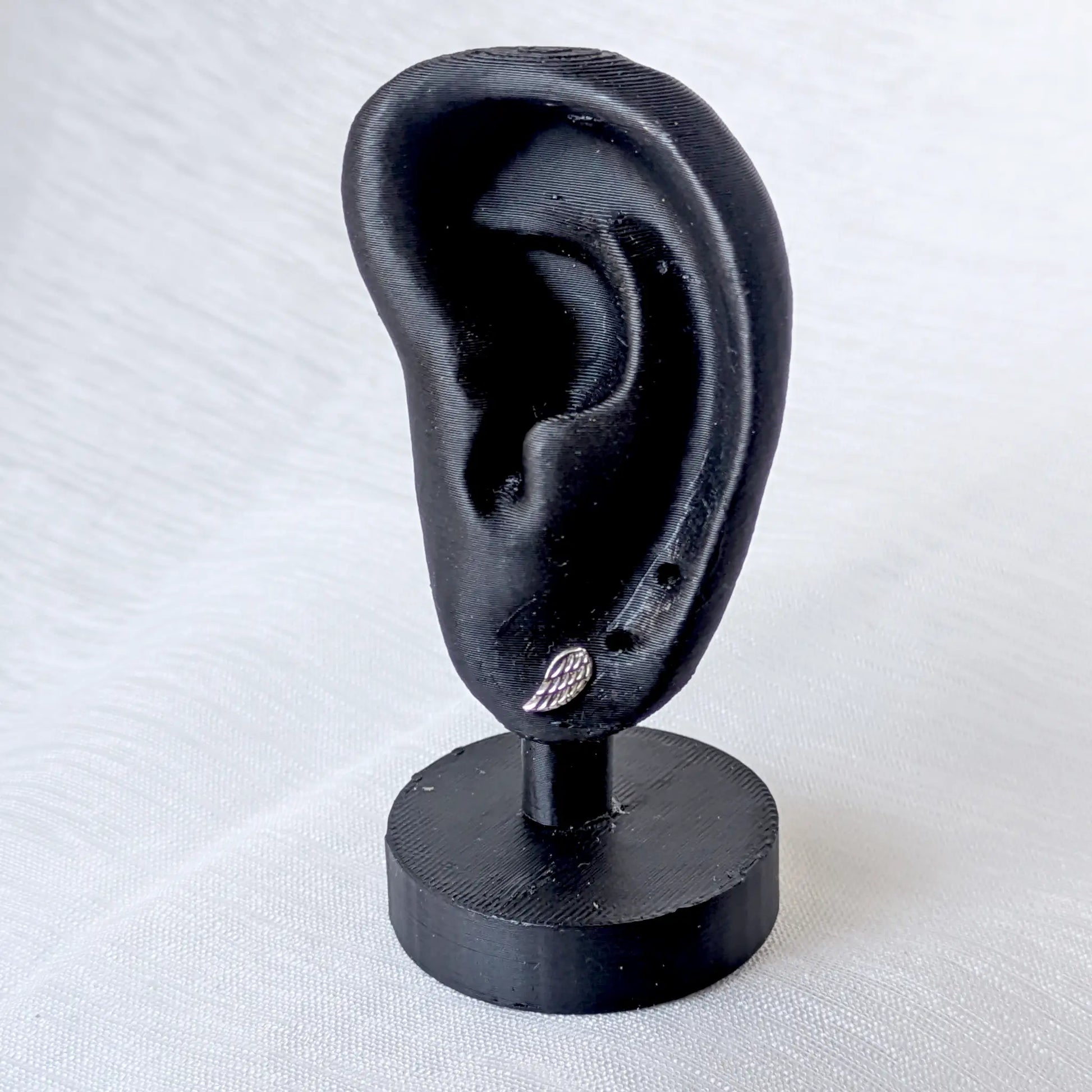 Filigraner Engelsflügel Ohrstecker aus 925 Silber getragen an einem schwarzen Ohr-Display.