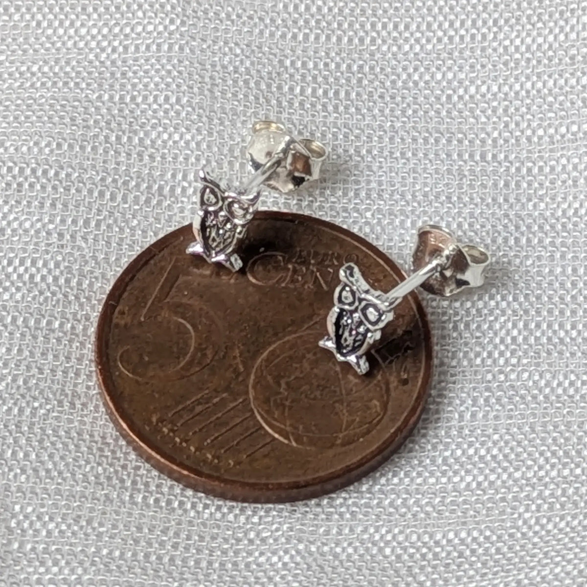 Größenvergleich der detaillierten Eulen-Ohrstecker aus Silber, flach liegend auf einer 5-Cent-Münze.