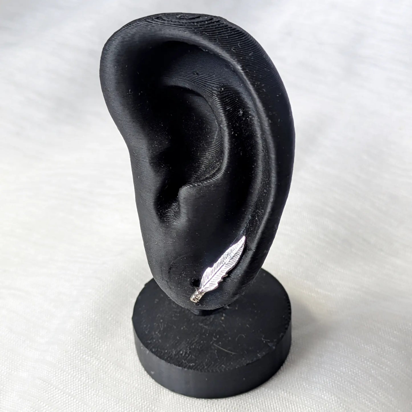Feder Ohrstecker aus 925 Silber getragen an einem schwarzen Ohr-Display zur Veranschaulichung der optimalen Größe am Ohrläppchen