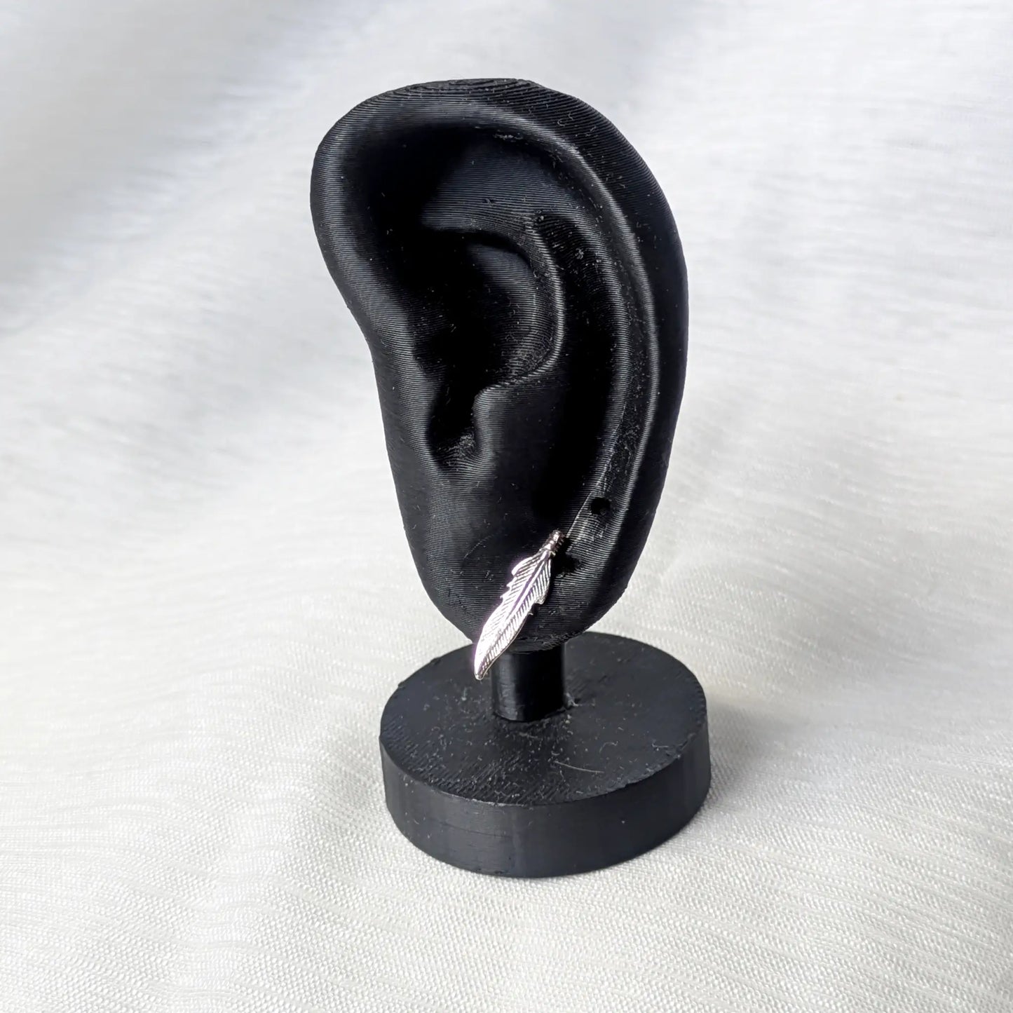 Feder Ohrstecker aus 925 Silber getragen an einem schwarzen Ohr-Display zur Veranschaulichung der optimalen Größe.