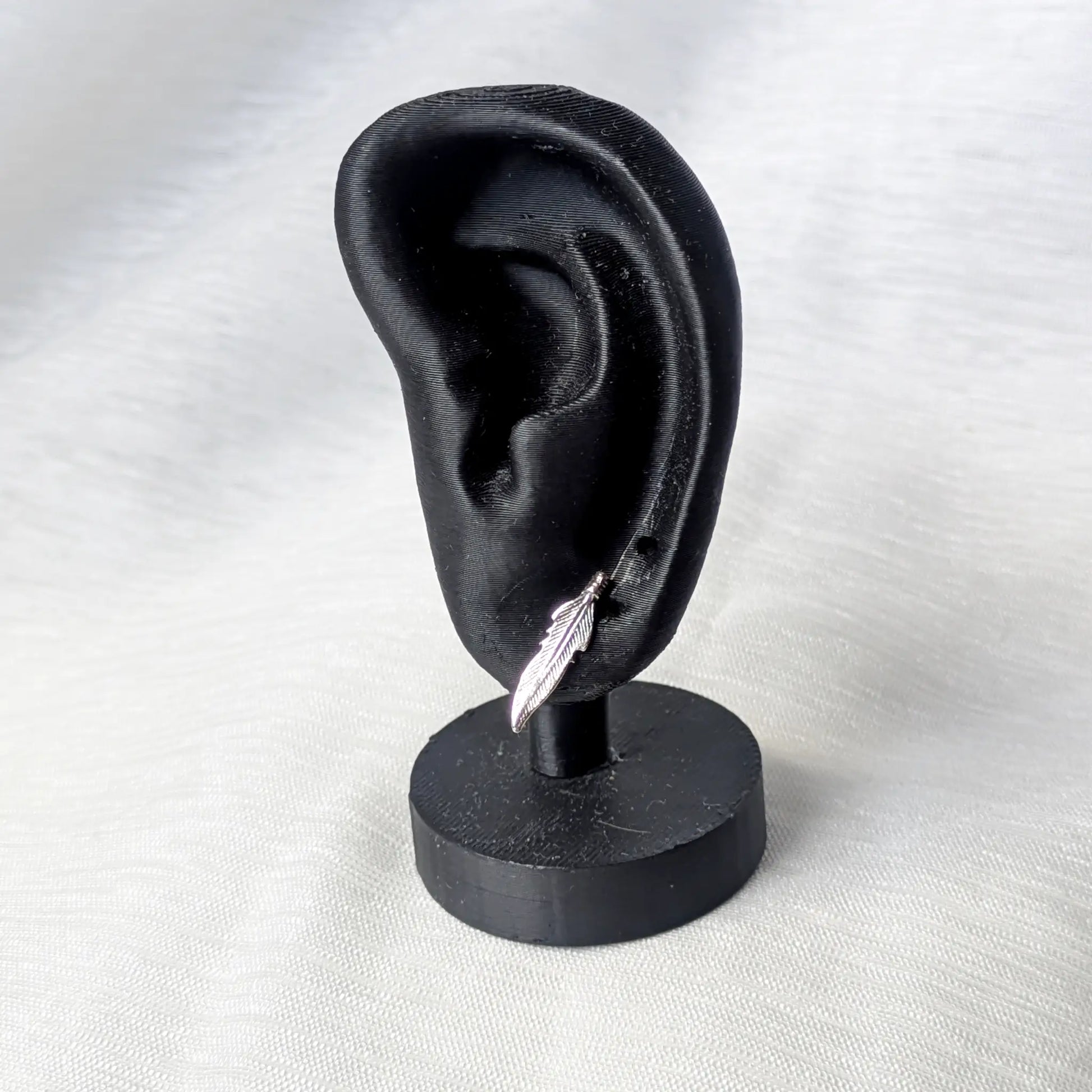 Feder Ohrstecker aus 925 Silber getragen an einem schwarzen Ohr-Display zur Veranschaulichung der optimalen Größe.